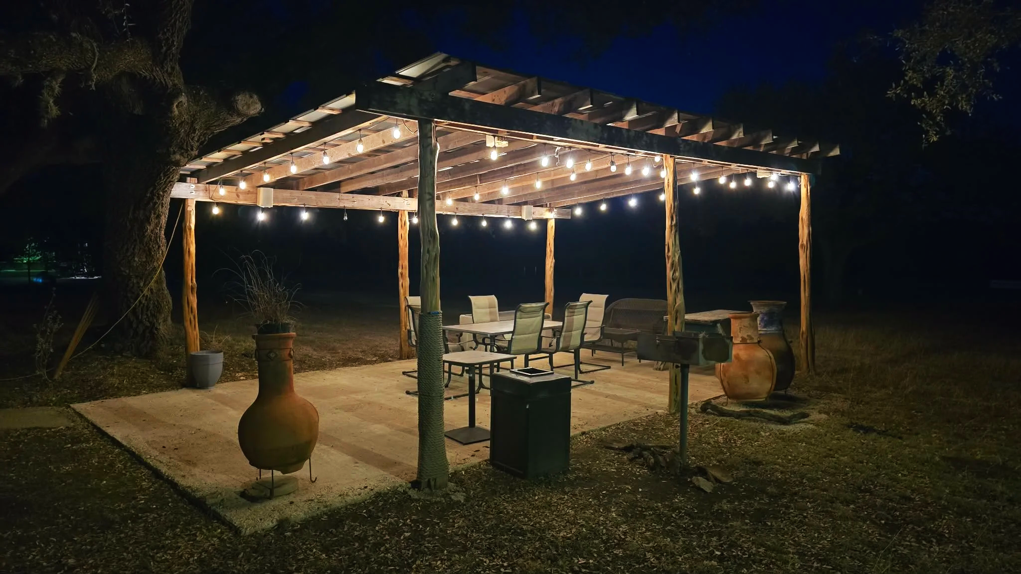 Image of the Swiss Lodge Motel outdoor gazebo at night. Under the gazebo is a sitting area and grill.