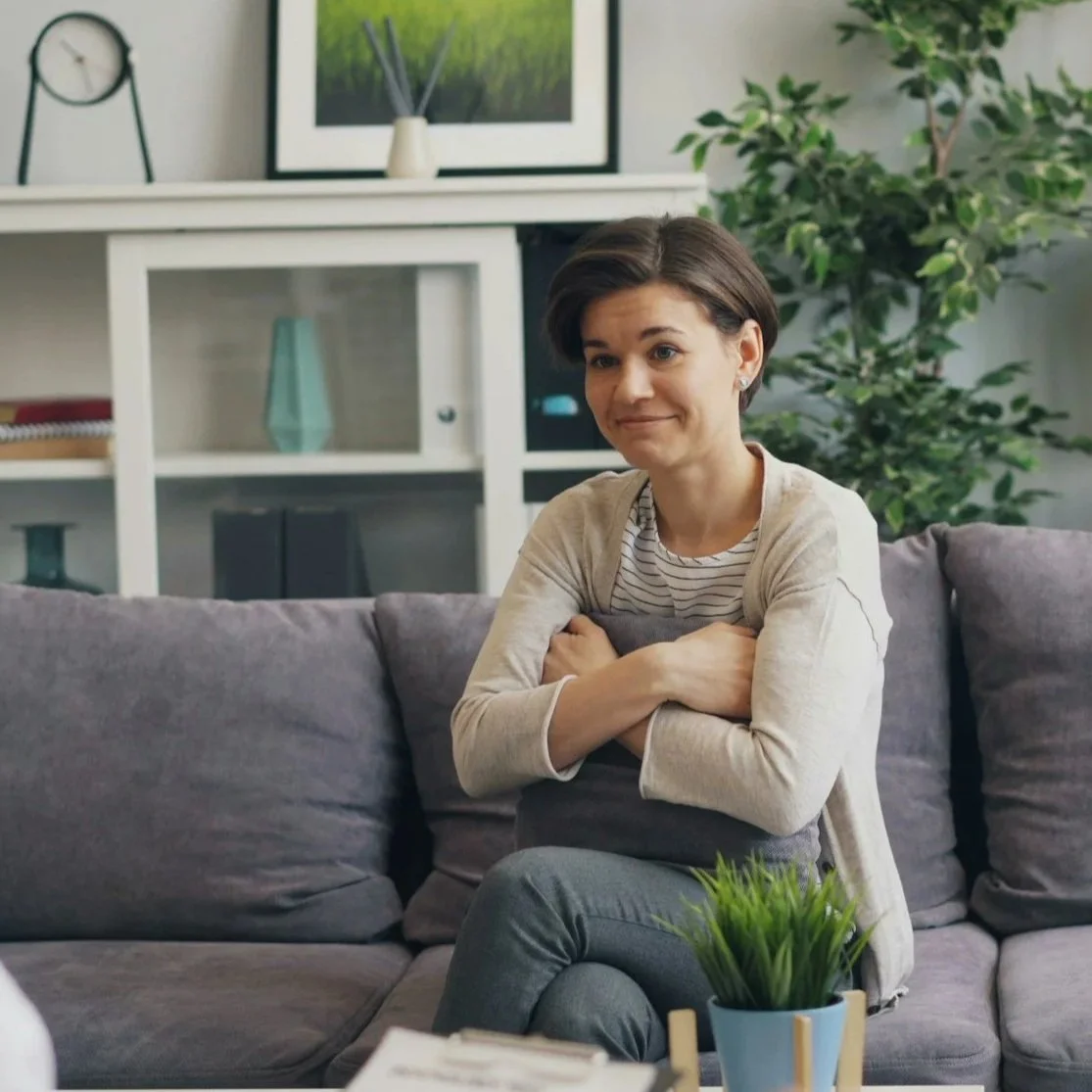 A stock photo of a woman sitting on a couch in an individual therapy session