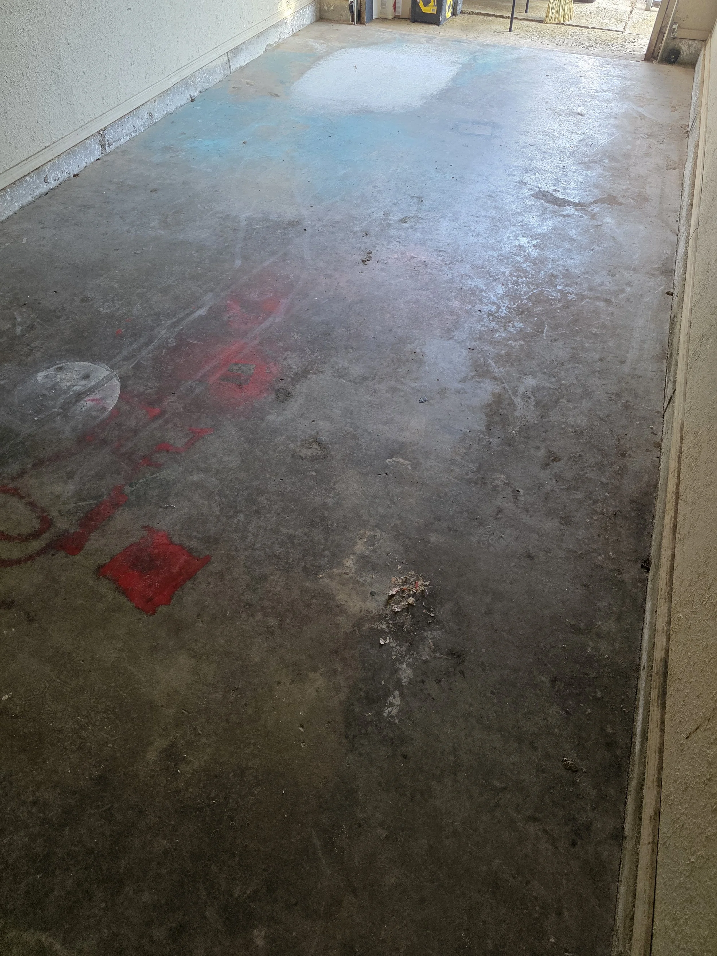 Close-up of the concrete condition prior to grinding. Paint, deep stains, and surface damage document why this floor needed a full system solution.