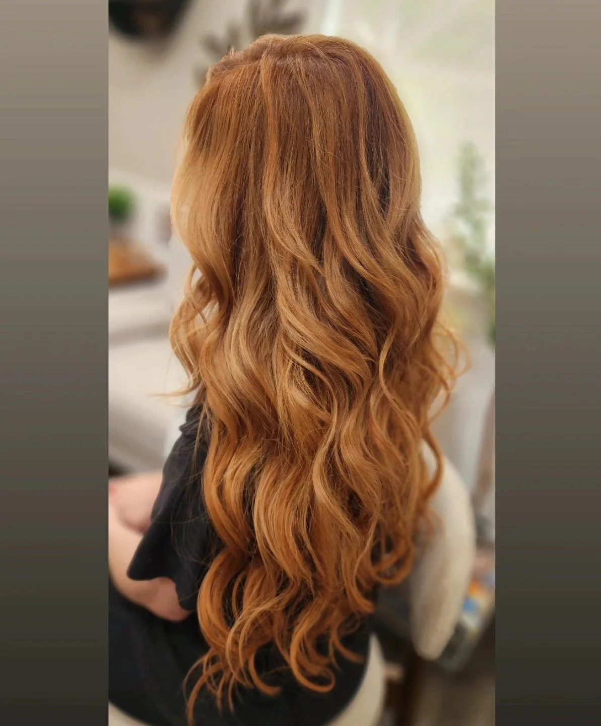 Back view of a woman with long, wavy, reddish-blonde hair.