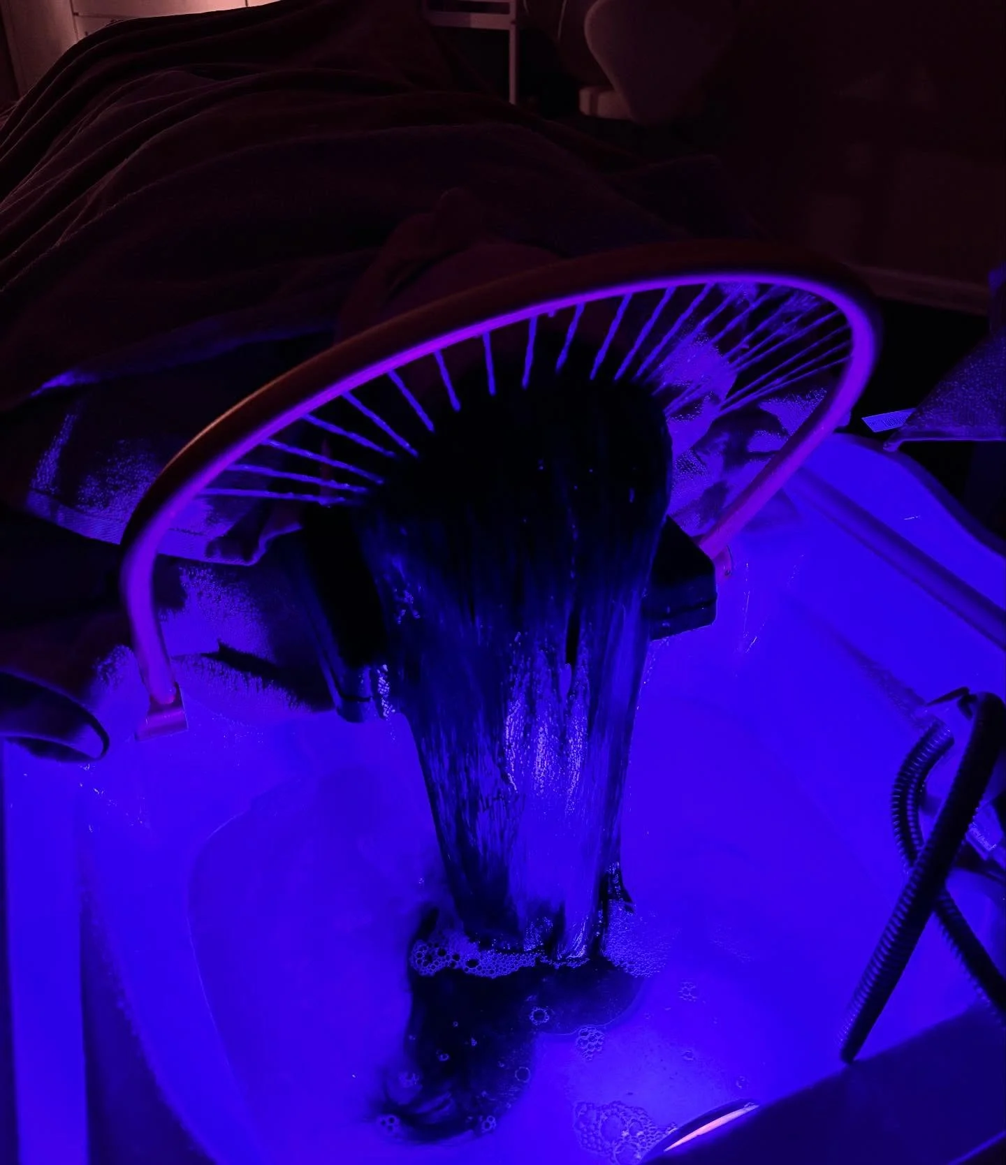 A hairdryer blowing blue LED light onto sudsy water with soap bubbles.