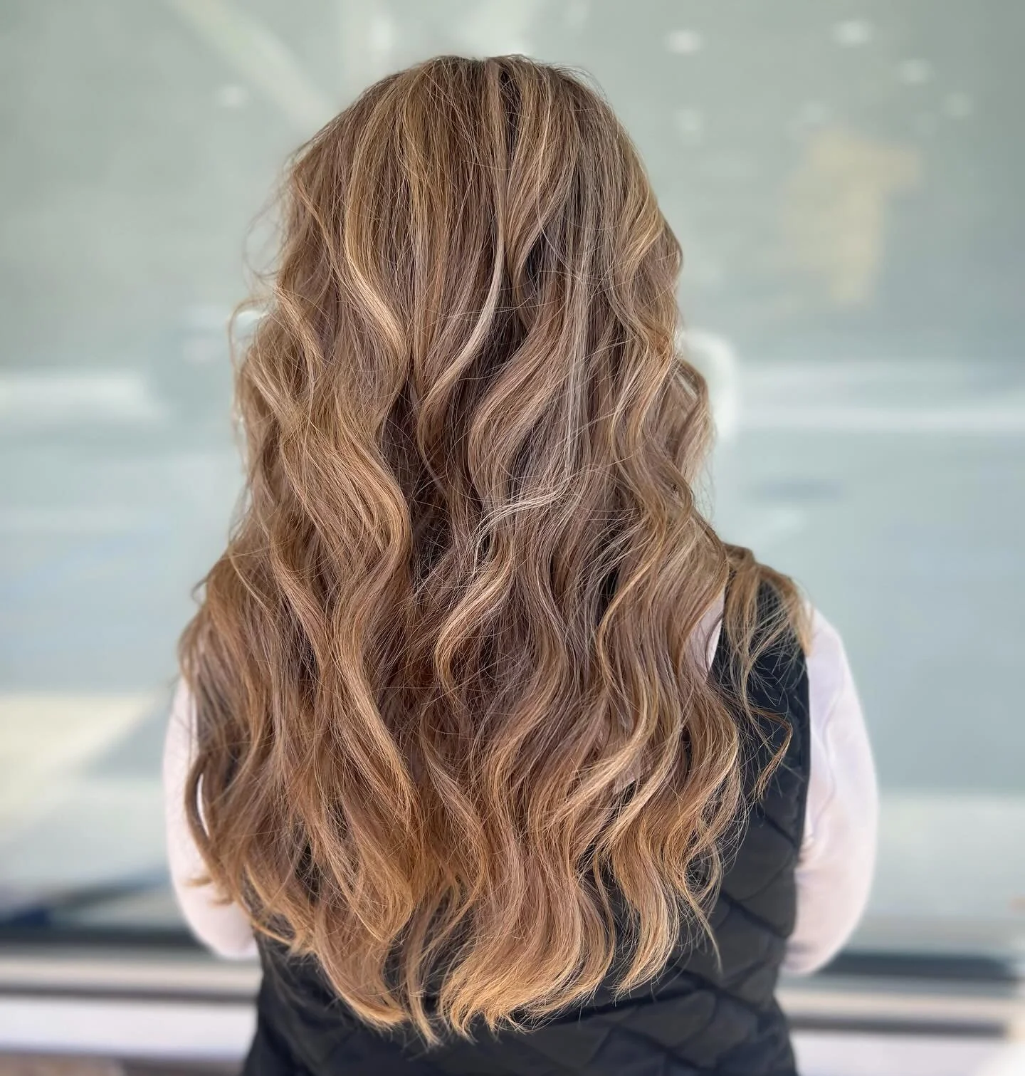 Back of a woman with long, wavy, light brown hair.