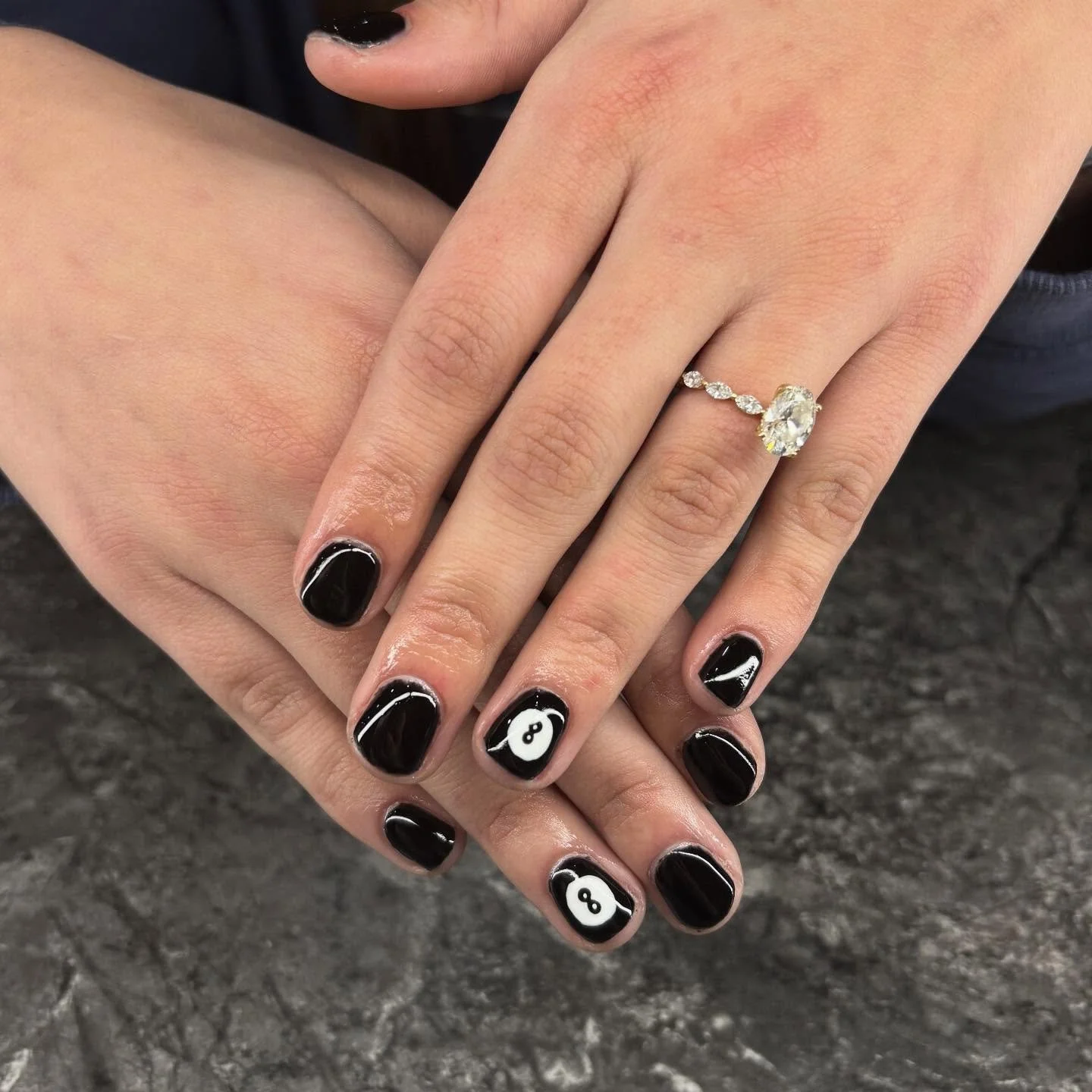 Close-up of a person's hands with black and white yin-yang patterned nail art, wearing a diamond ring with a prominent oval gemstone.