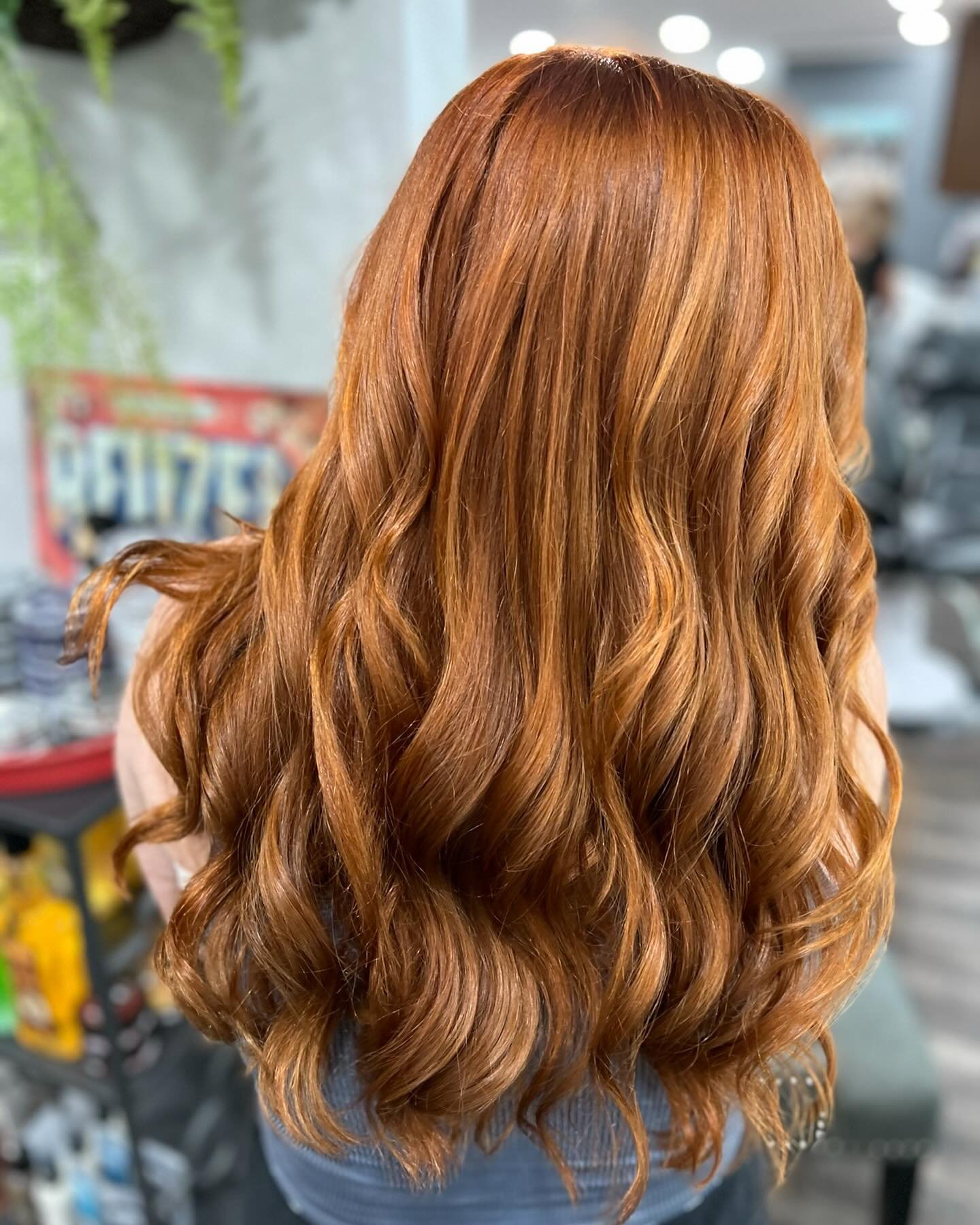 Back view of a person with long, wavy, reddish-brown hair.