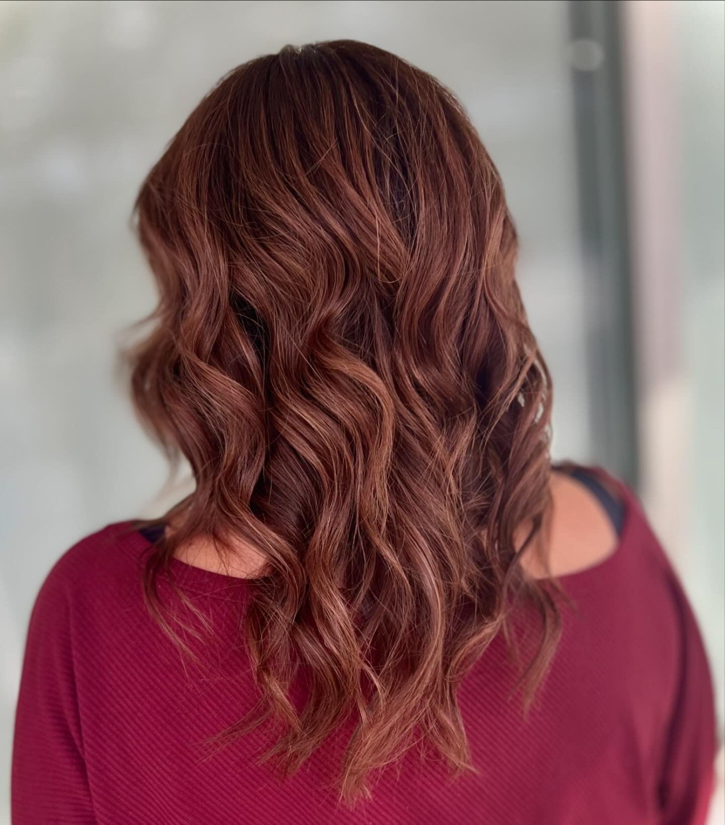 Woman with wavy, reddish-brown hair wearing a maroon top.