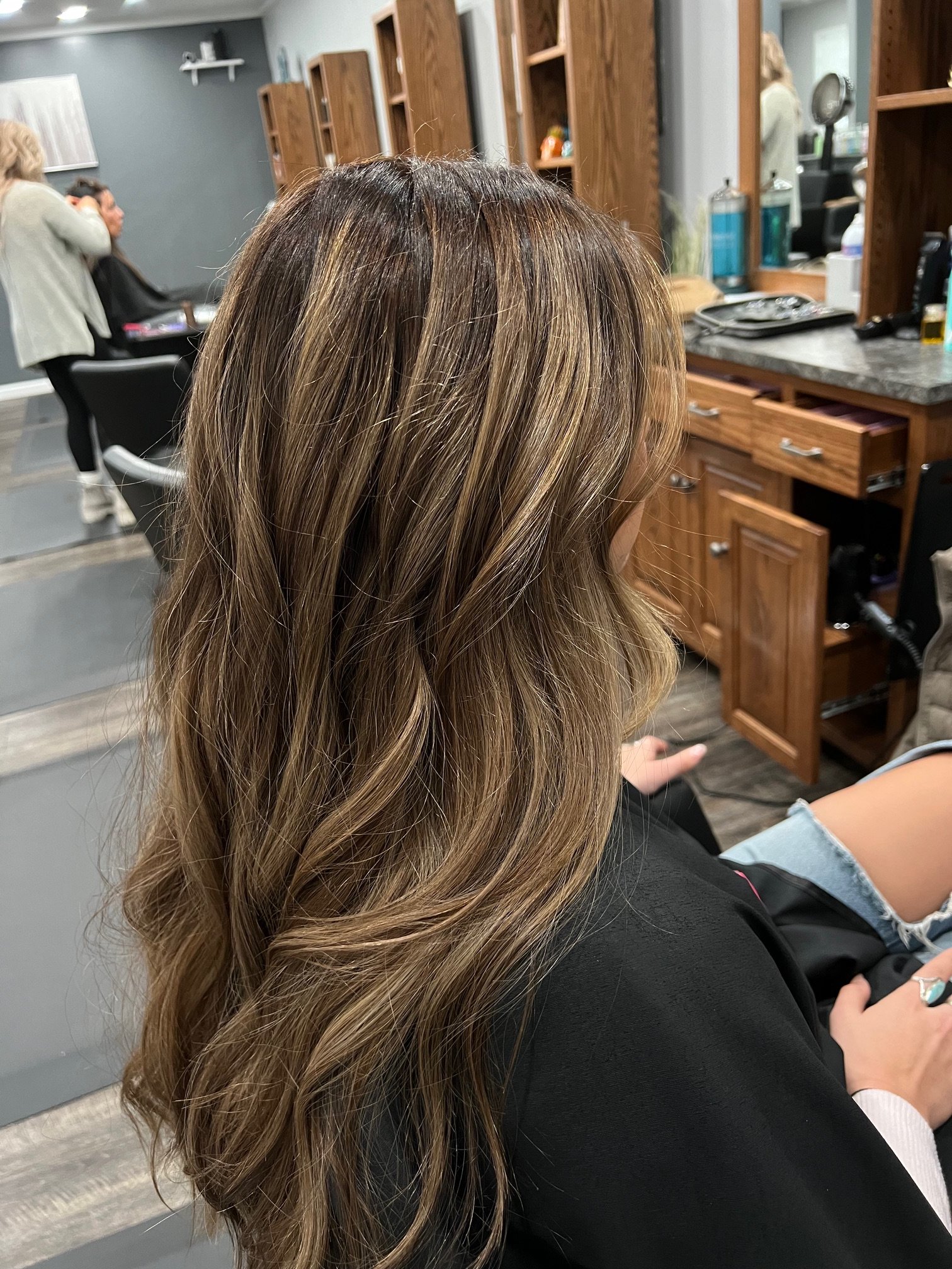 Hair with brown and blonde highlights, wavy style, in a salon setting.