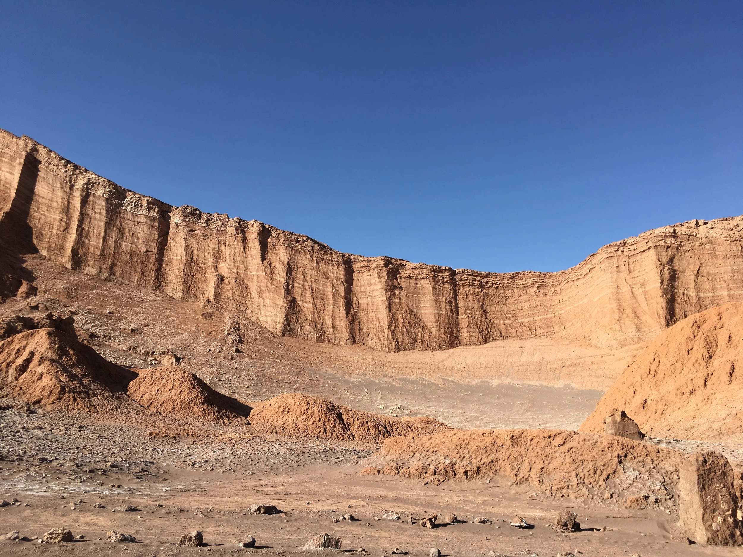 Desert landscape with tall, rocky cliffs under a clear blue sky.