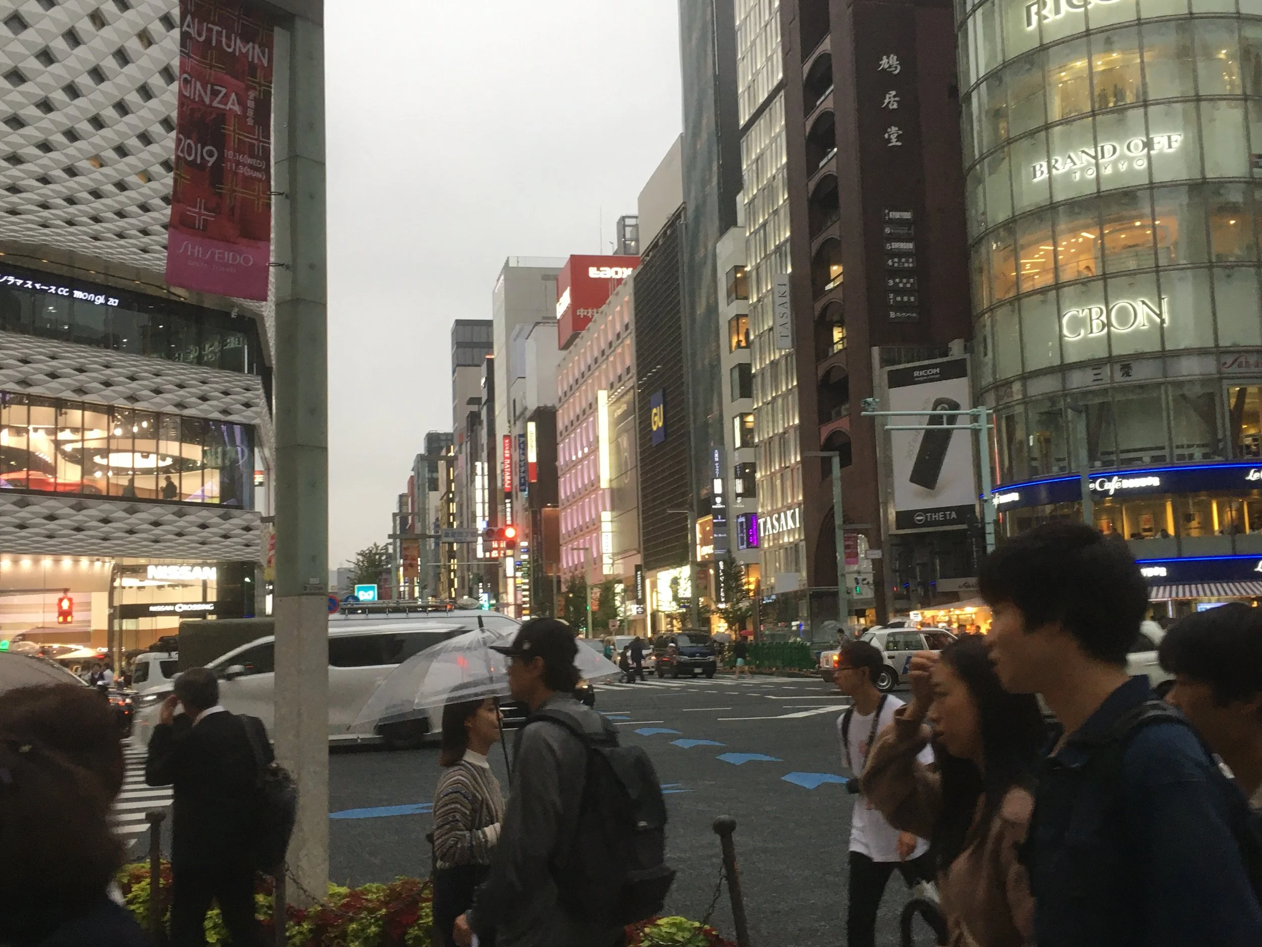 City street scene with pedestrians, cars, and bright building signs