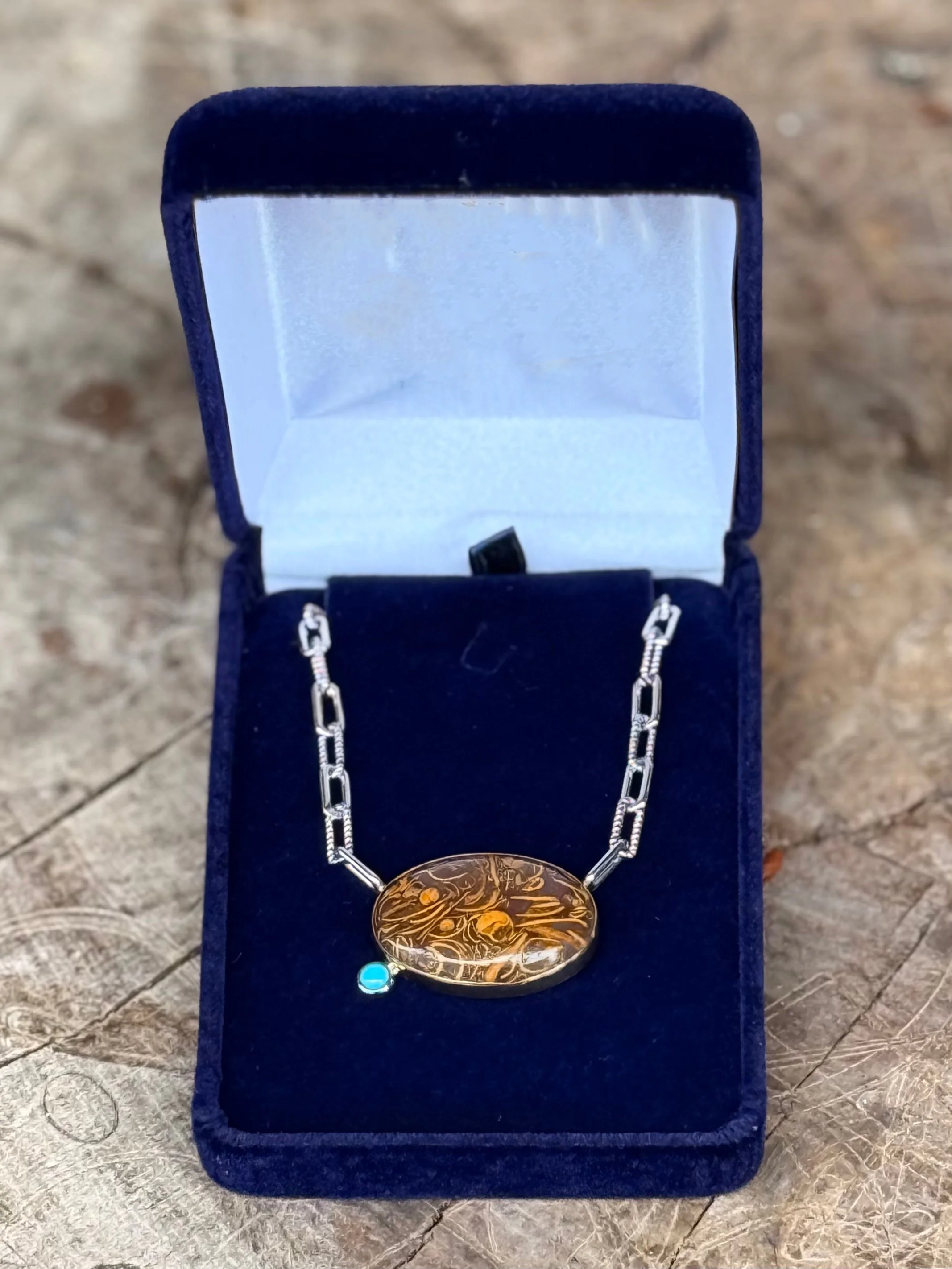 Handcrafted two-tone pendant necklace with engraved gold disc and turquoise accent on mixed metal chain displayed in velvet jewelry box