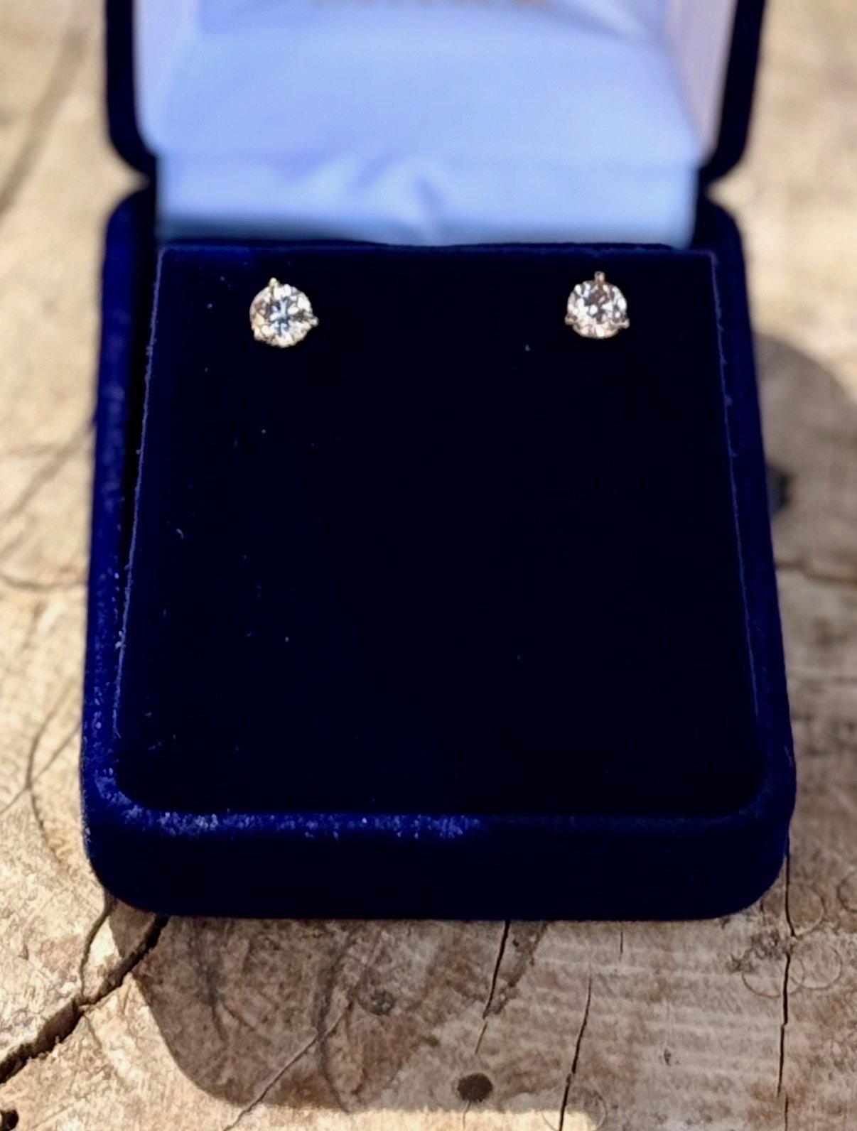 Diamond stud earrings in a blue jewelry box with a velvet interior.