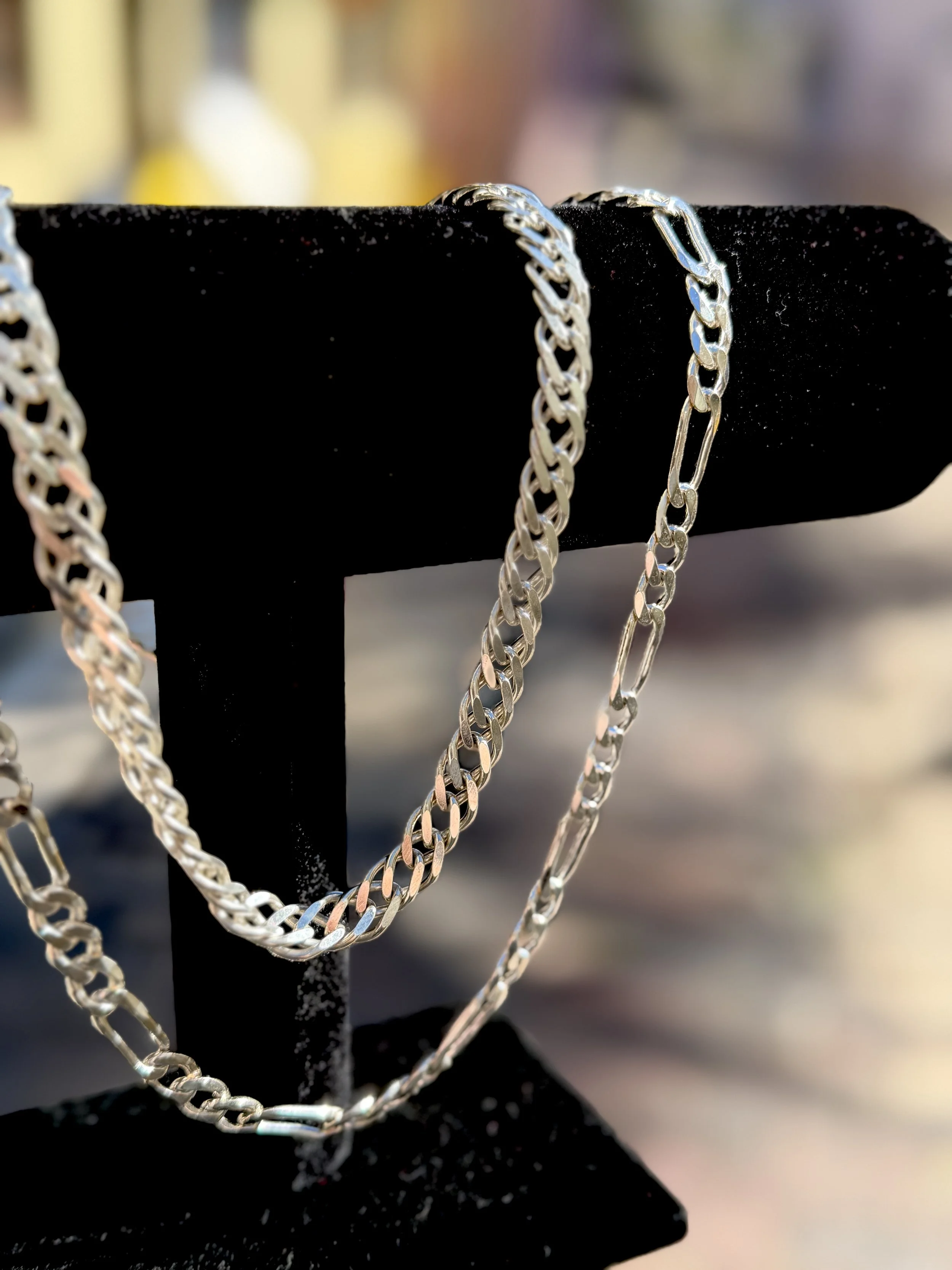 Silver chains hanging on a black display stand.