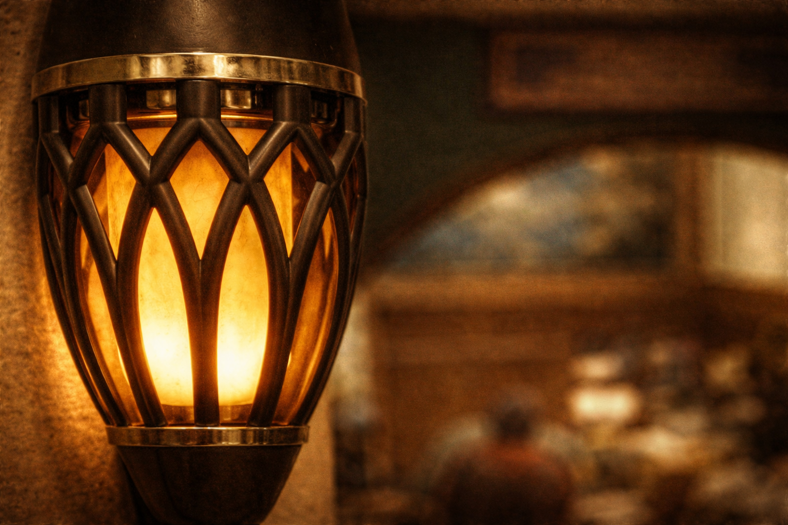 Decorative wall sconce light fixture with a metal lattice design emitting a warm glow in an interior setting.
