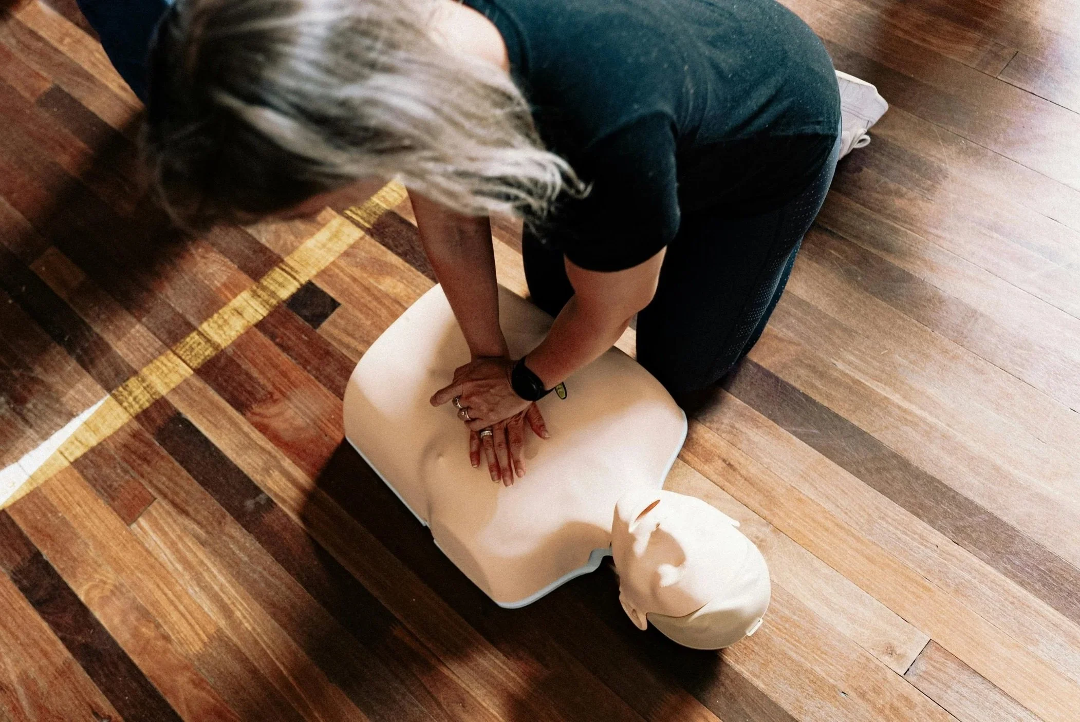 Person performing CPR on a mannequin during a training session.