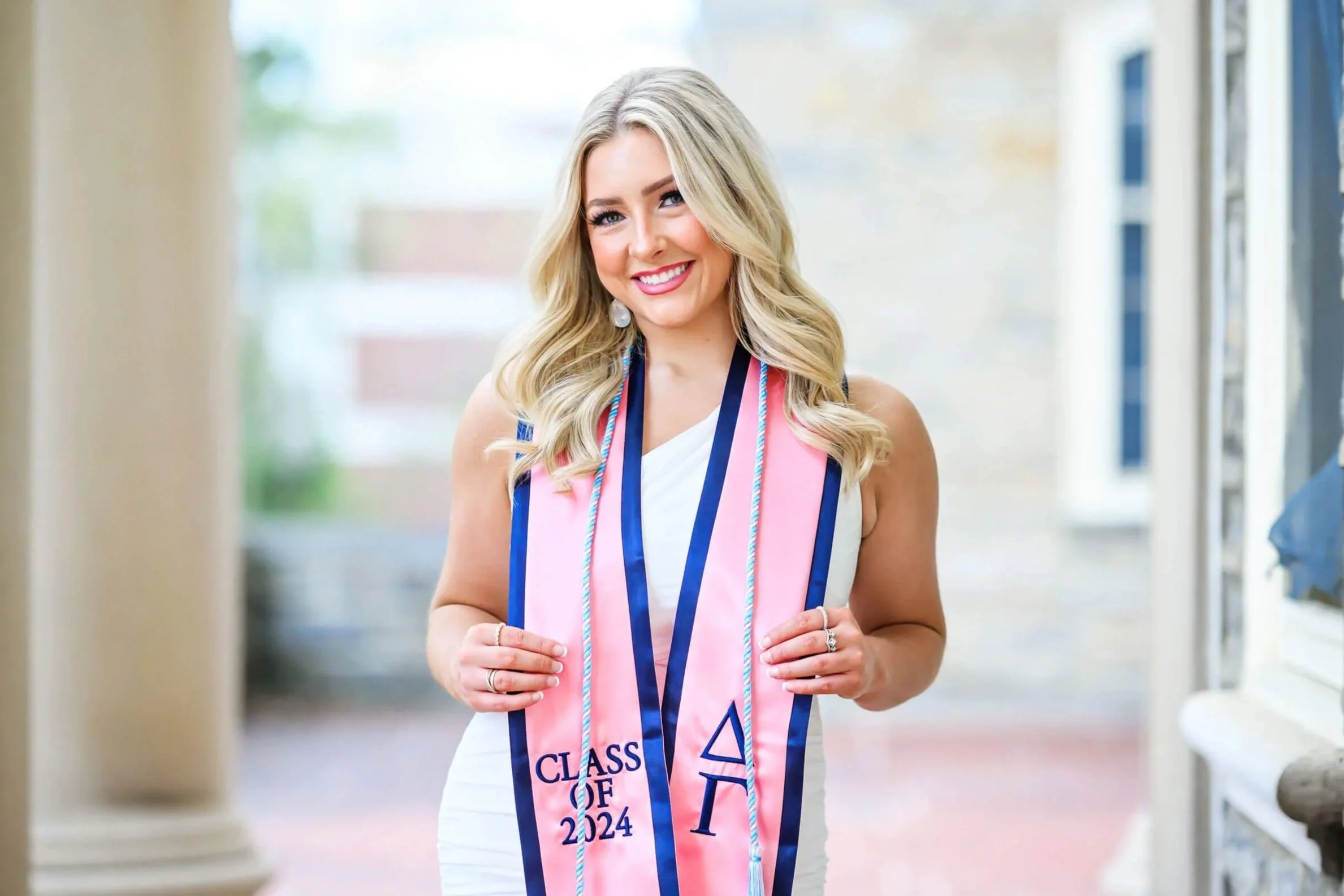 Penn State graduate with white dress holding pink sorority stole at Old Main during a Tish O’Connor Photography session