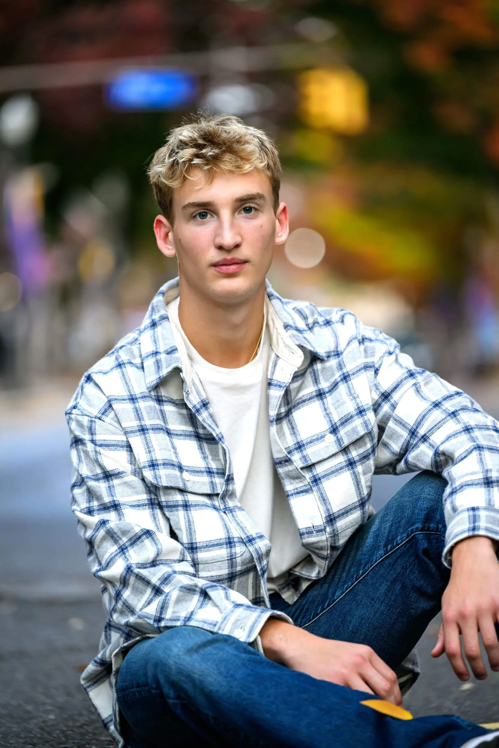 Young man in a plaid flannel shirt sitting on the ground, urban fall backdrop.jpg
