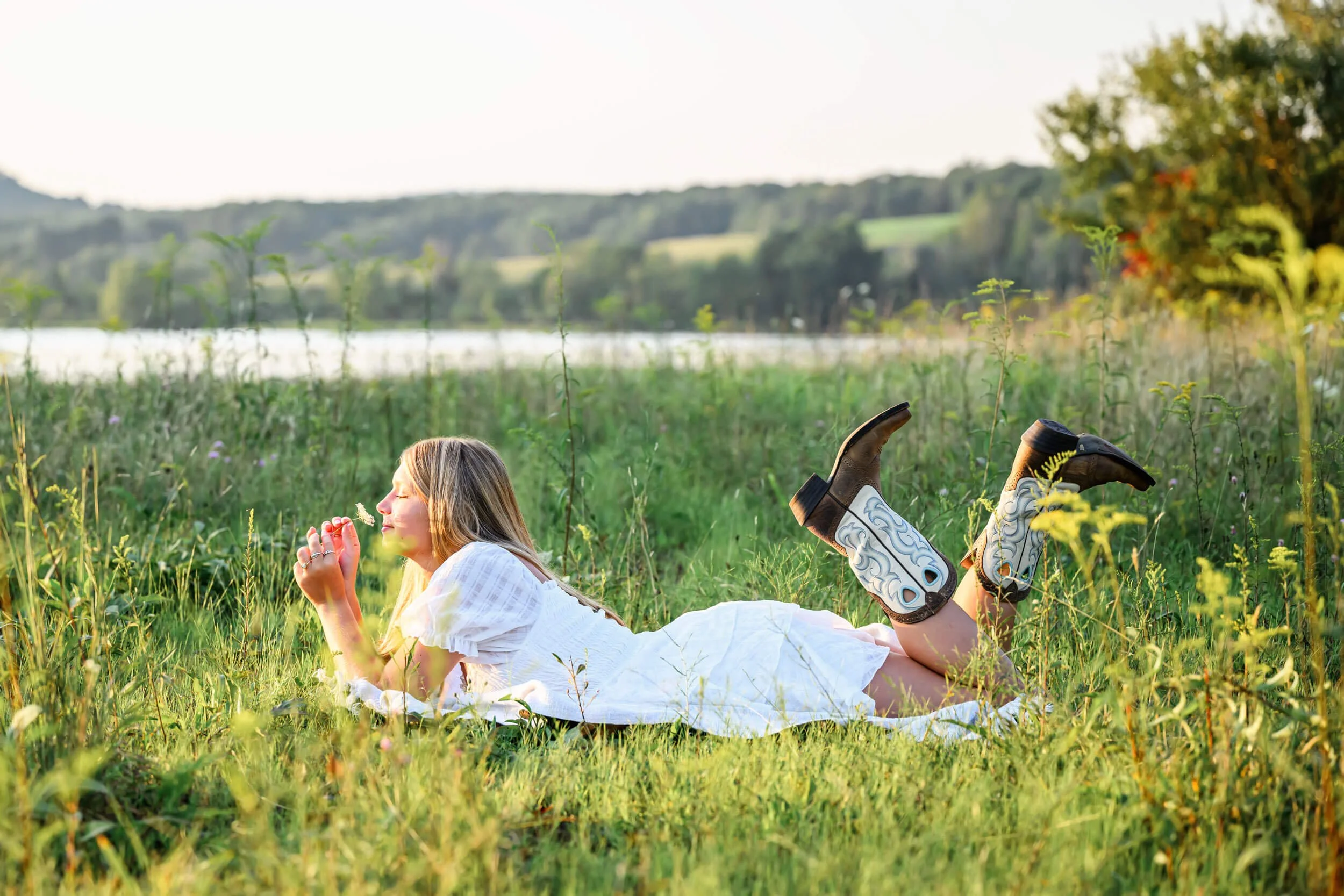 Young woman in a white dress and cowboy boots lying in a field.jpg