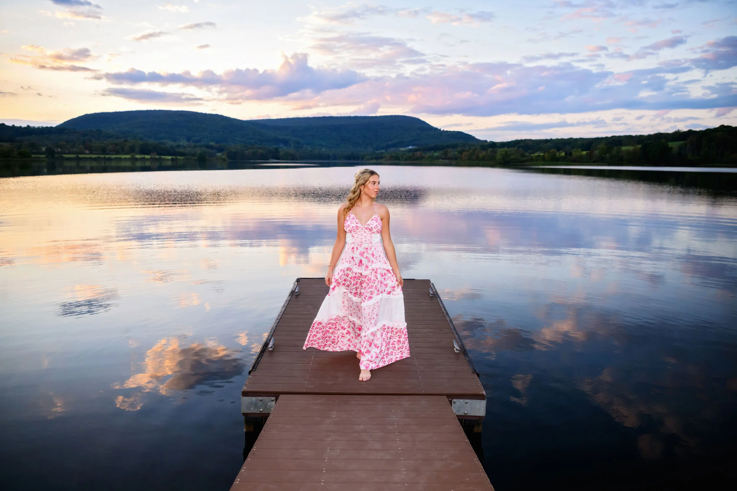 High school senior portrait sitting on a dock at sunset during an outdoor senior session in Williamsport, Pennsylvania.