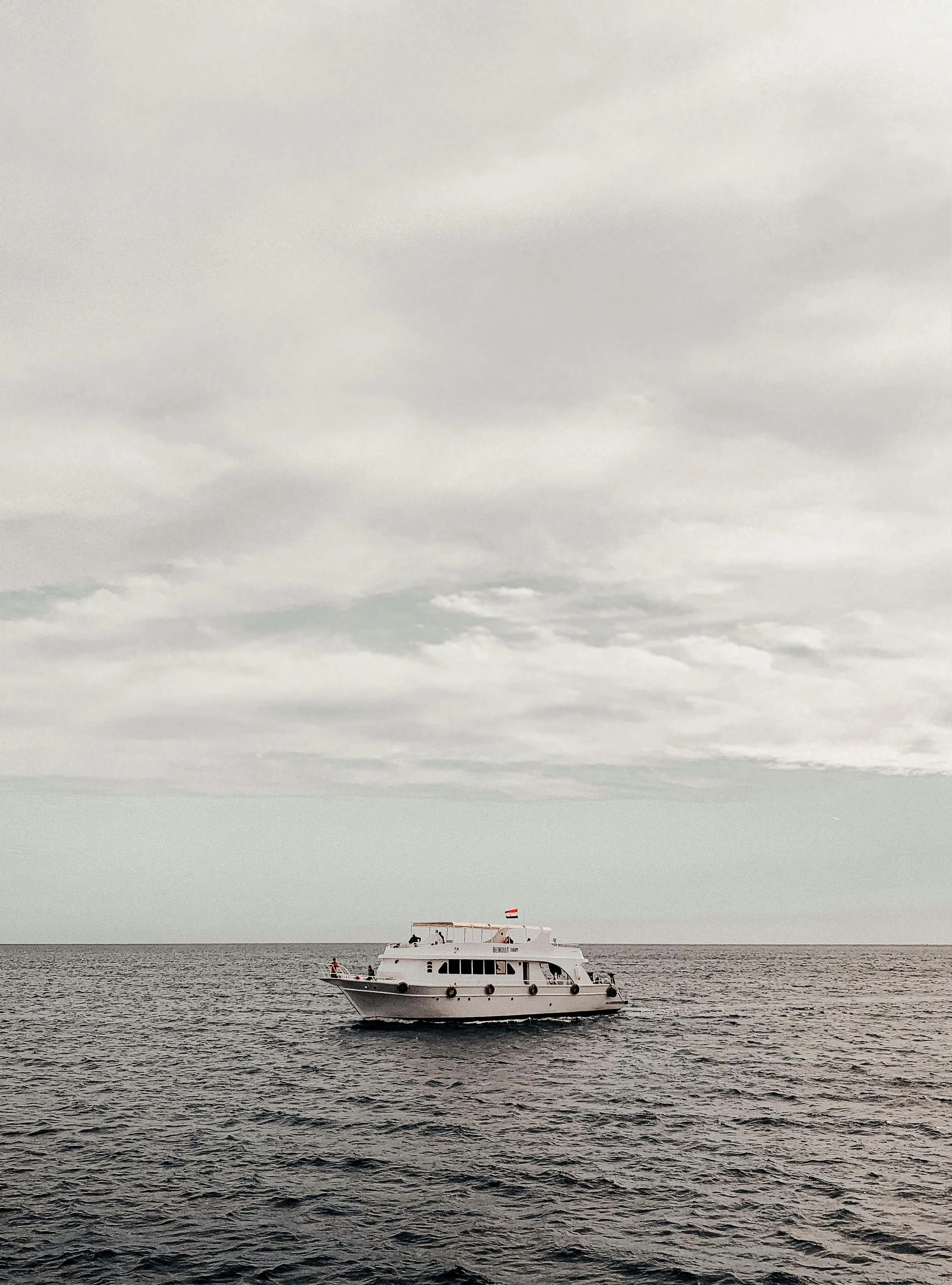 A white boat sailing on the open water under a cloudy sky.