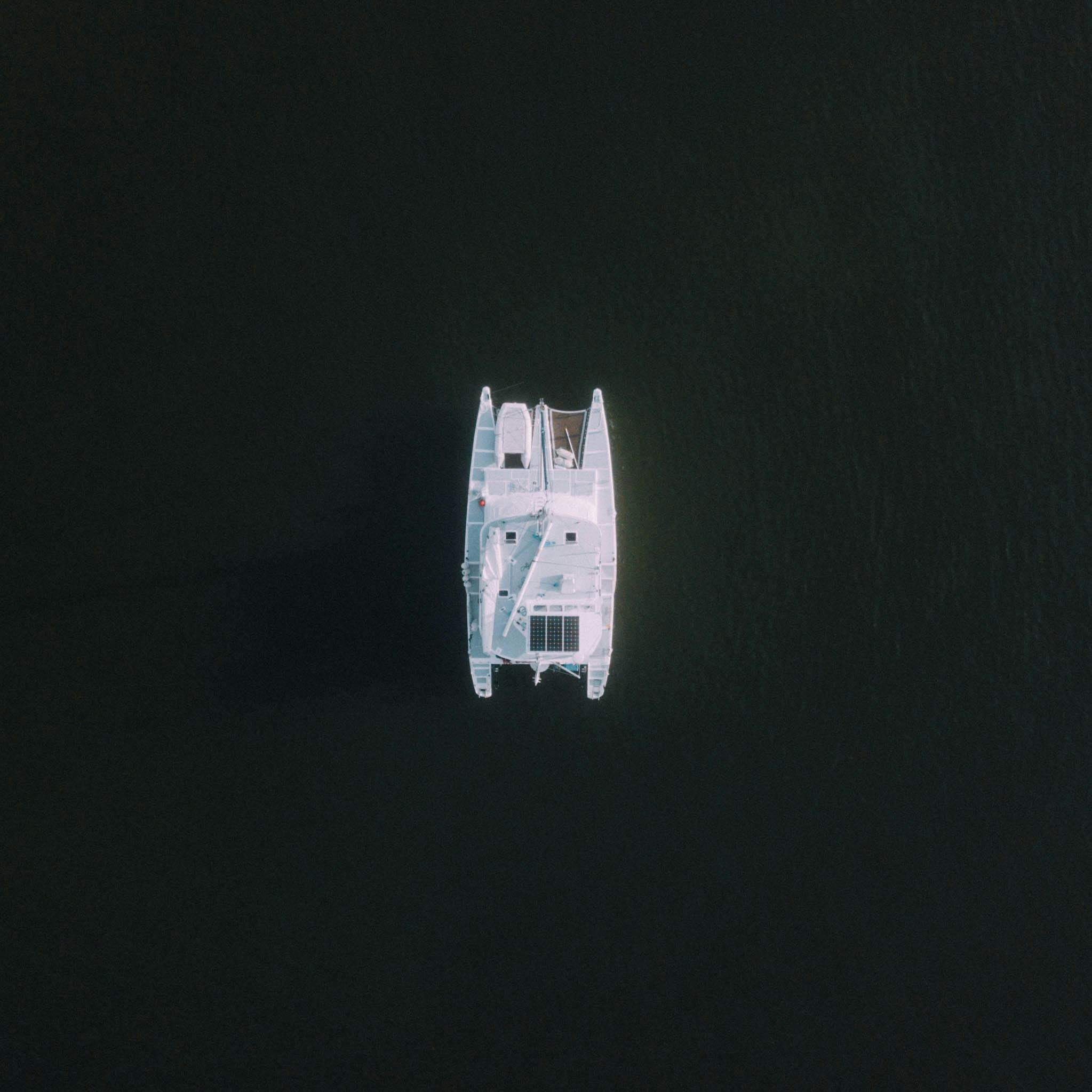 Overhead view of a white yacht floating on dark water.