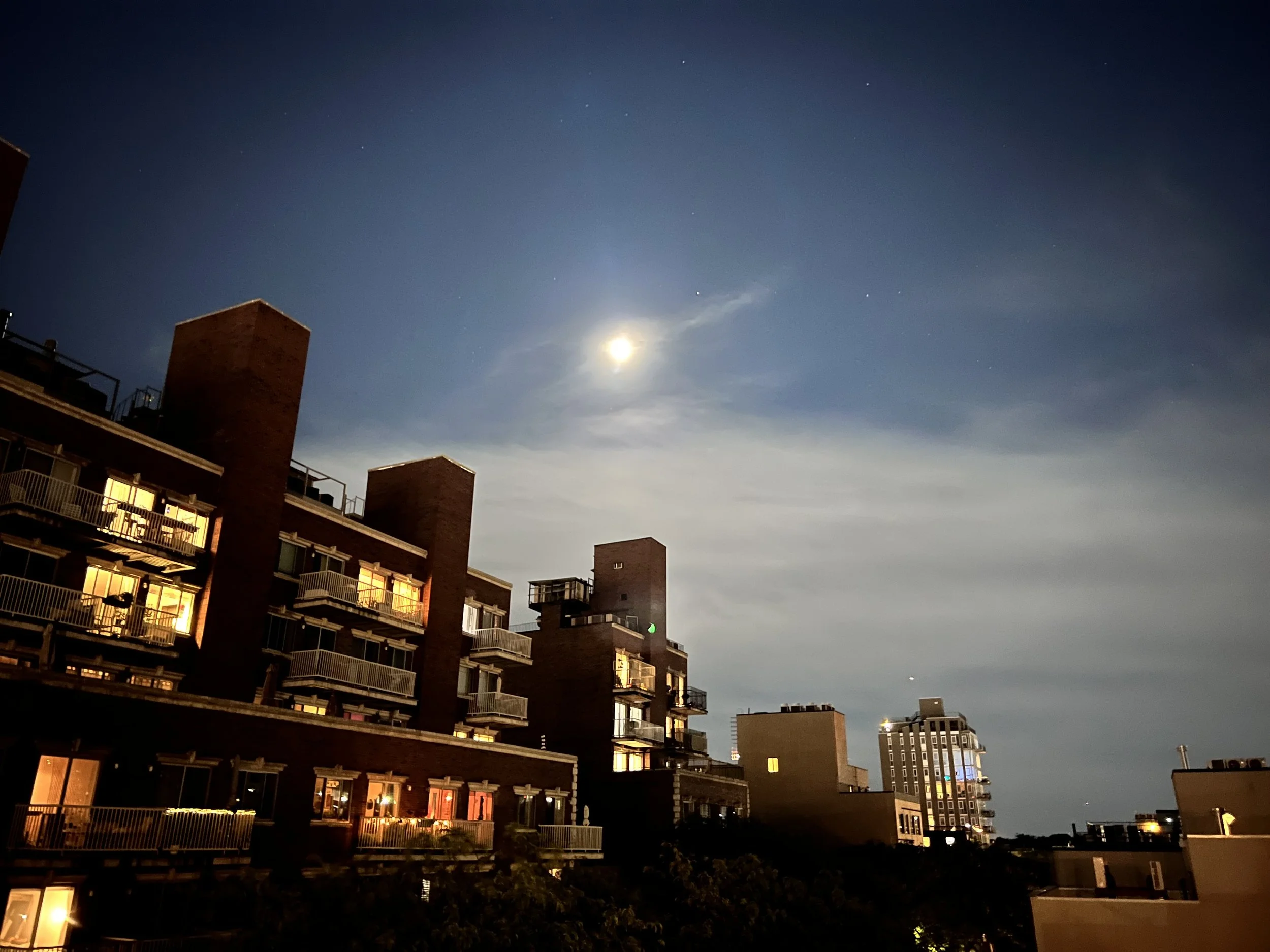 Nighttime scene of apartment buildings under a moonlit sky with visible stars.