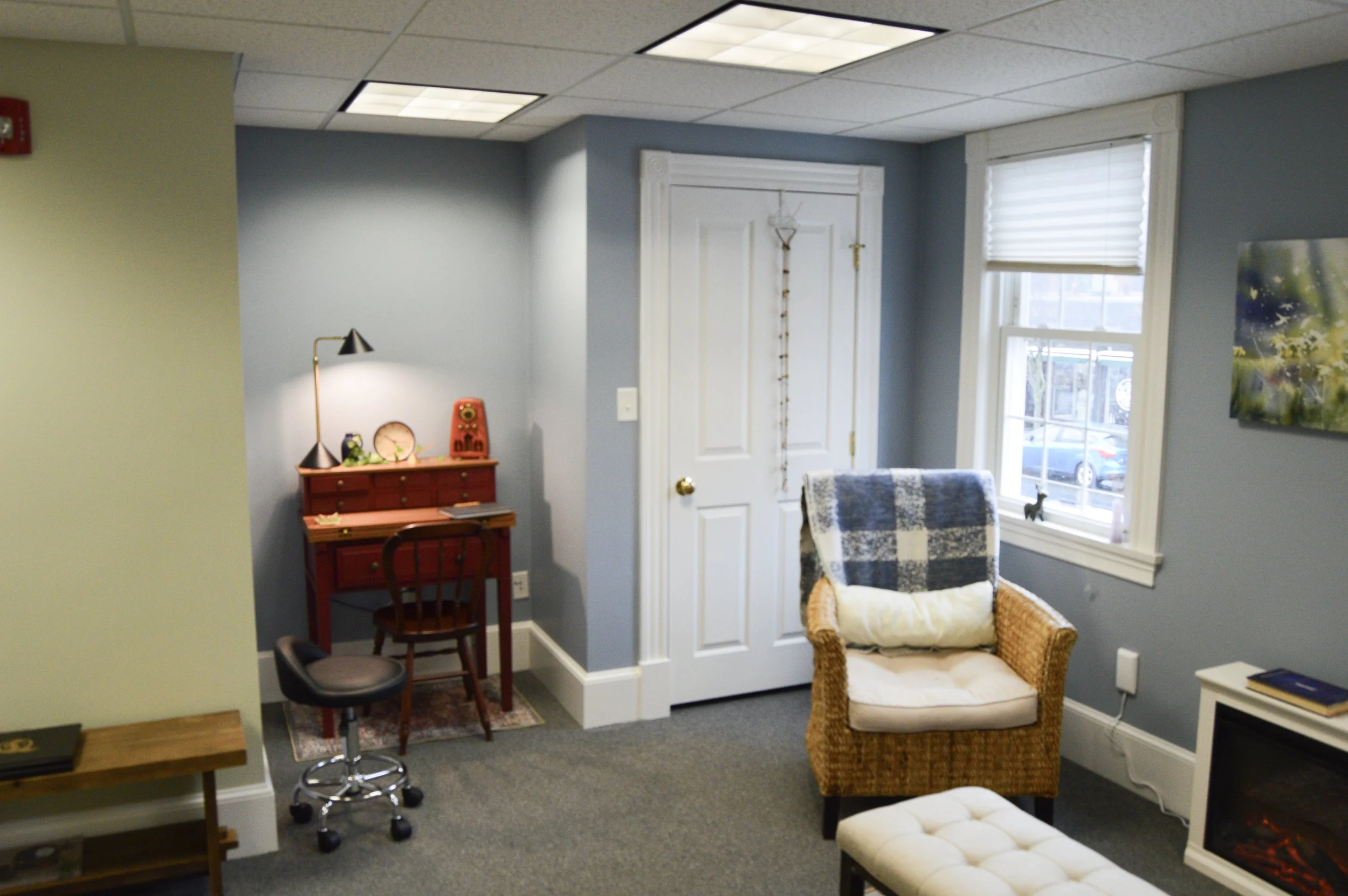A cozy window seat with cushions and a flower box, overlooking a lush garden with trees.