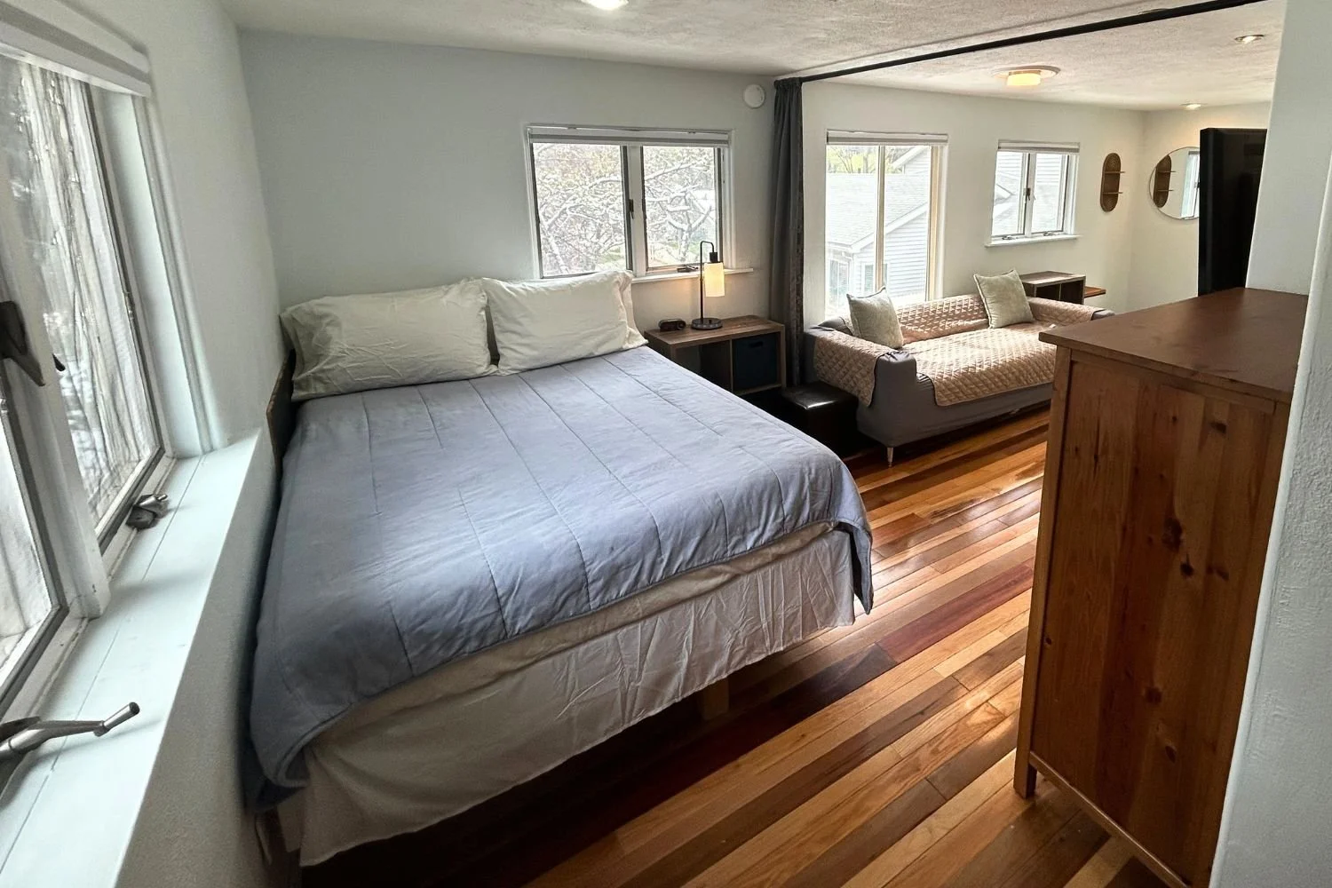 Bedroom with a large bed, window seats, and a sitting area with a sofa and cushions.