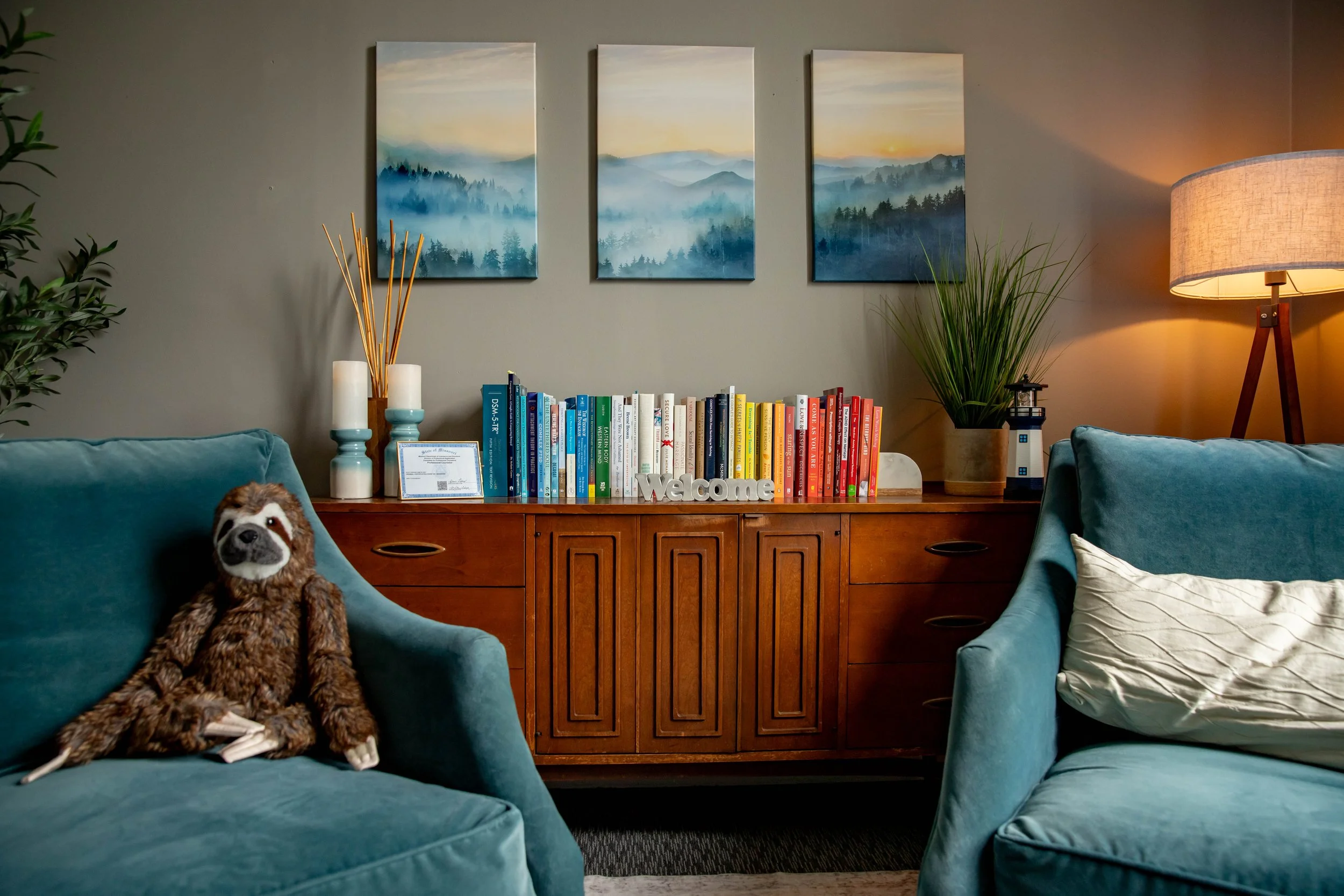 View of therapy office with two chairs, credenza, soft lighting, and a soft, plush sloth