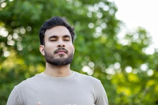 young-man-engages-in-mindfulness-and-relaxation-exercises-standing-outdoors-with-eyes-closed-captures-peaceful-moments-of-meditation-and-wellness-highlighting-focus-on-breathing-photo.jpg