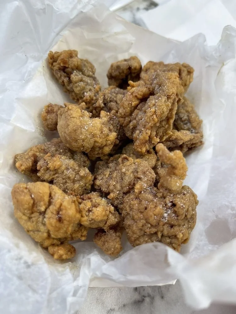 A close-up of several pieces of fried chicken on white paper.