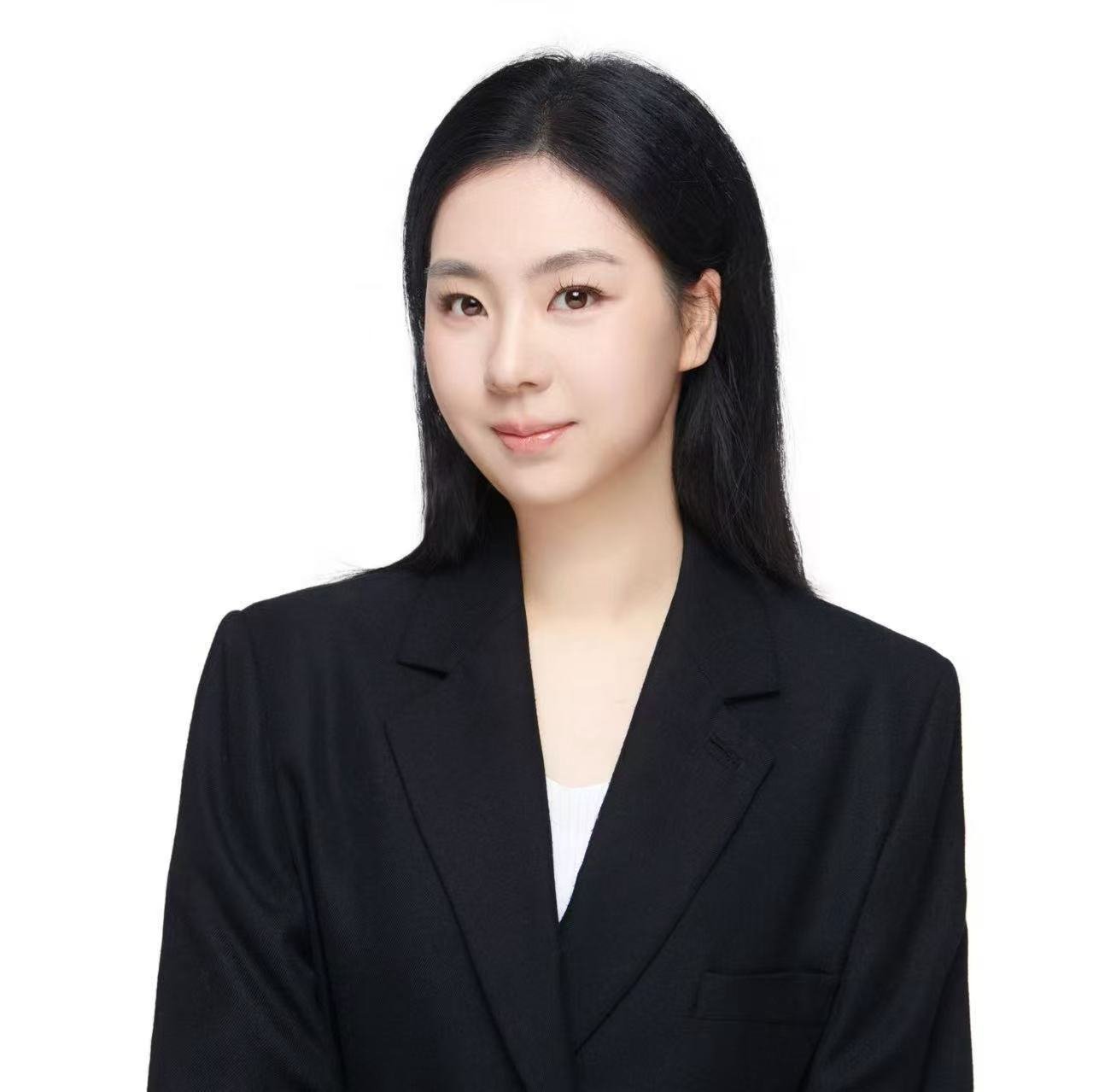 Portrait of a young East Asian woman with long black hair, wearing a black blazer, against a plain white background.