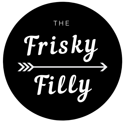 Black circular logo with white text that says "The Frisky Filly" and a white arrow pointing to the right.