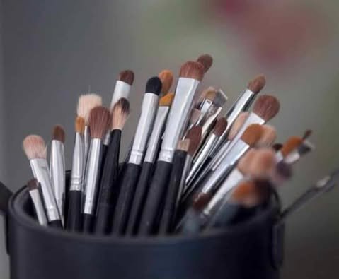 A collection of makeup brushes in a black container.