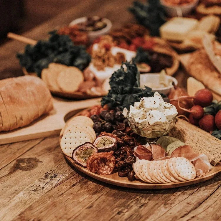 Cheese and charcuterie platter with crackers, grapes, and dried figs on a wooden table.