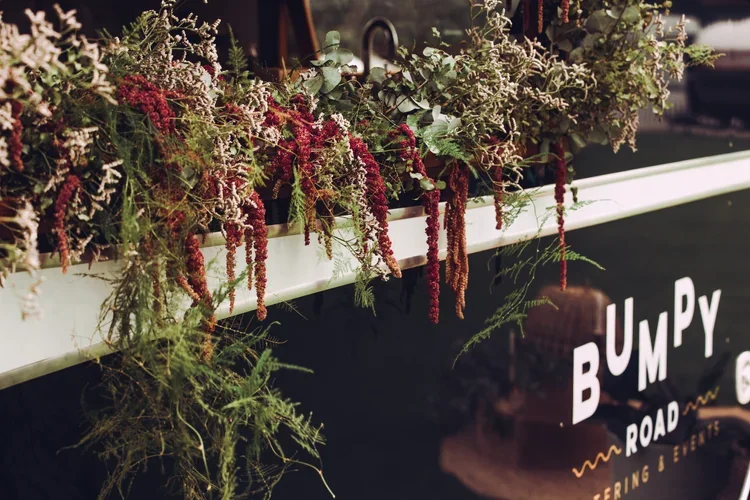 Arranged flowers and greenery on a display board at Bumpy Road, a catering and events venue.