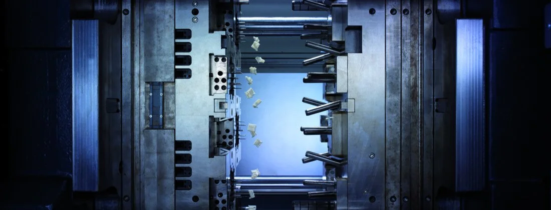 A metallic industrial mold with plastic flakes or parts inside, used in manufacturing or injection molding processes.