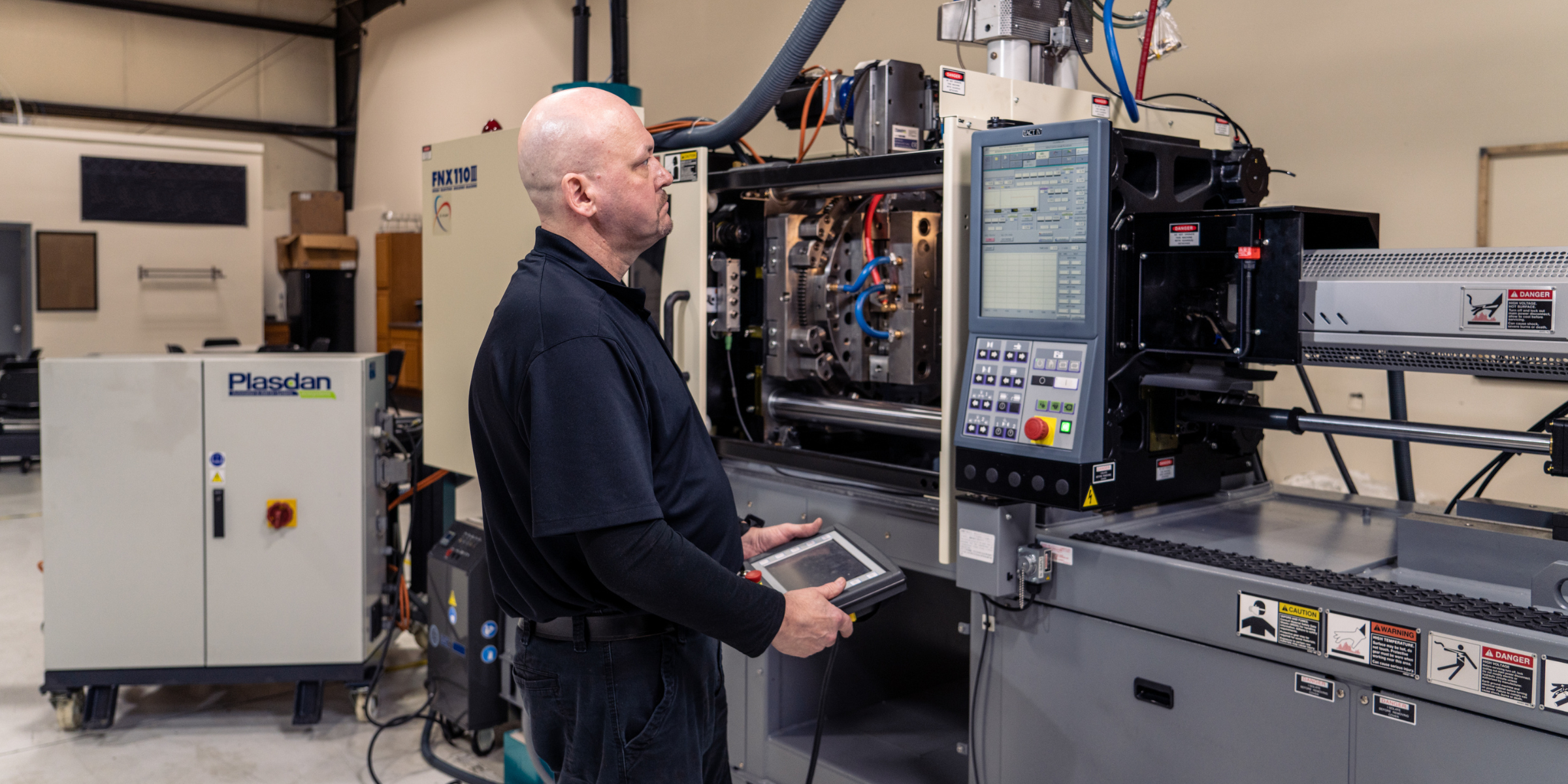 A man operating industrial machinery with a control panel, in a manufacturing or industrial setting.