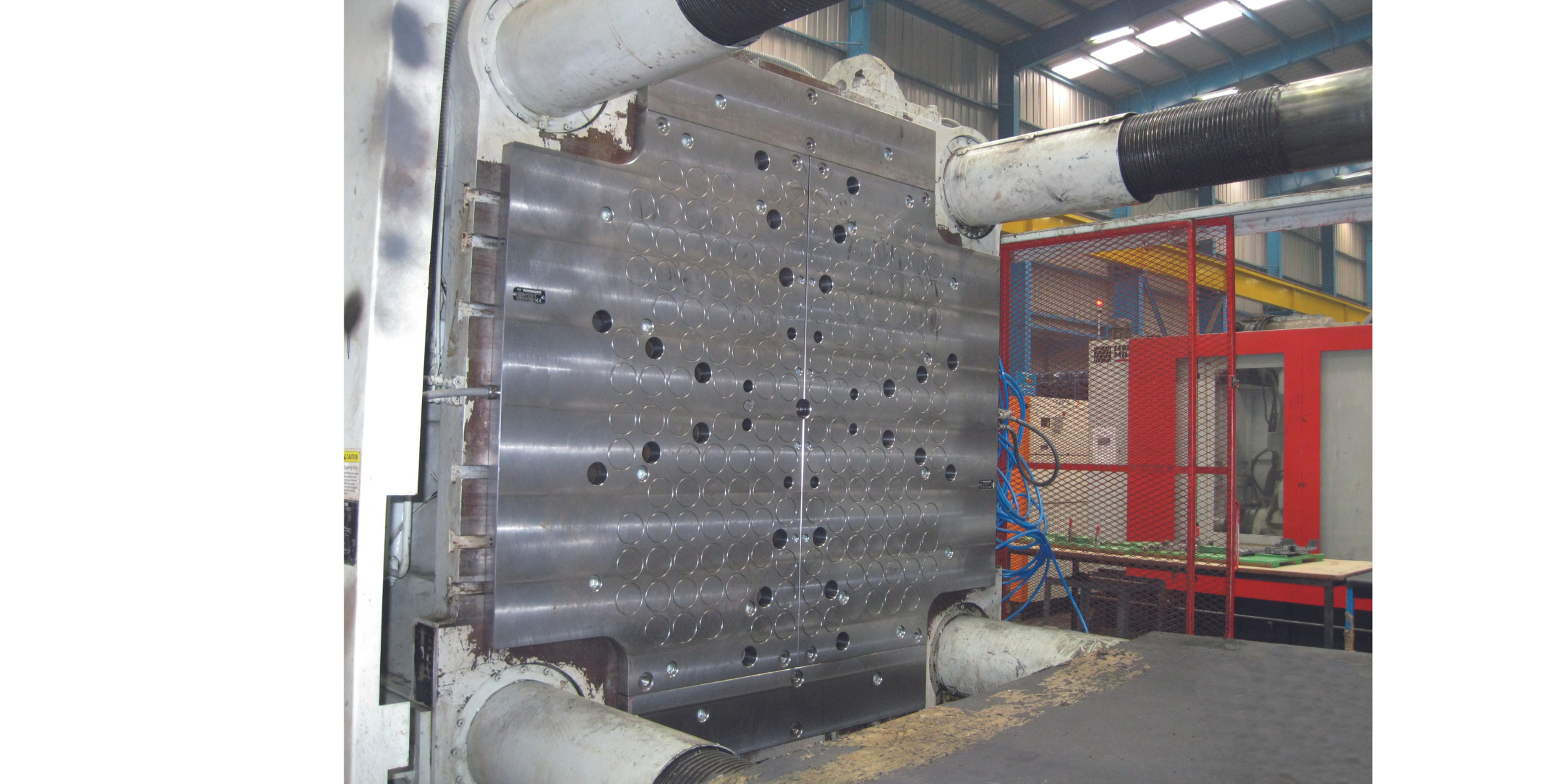 Industrial manufacturing machine with a metal mold and connected machinery in a factory setting.