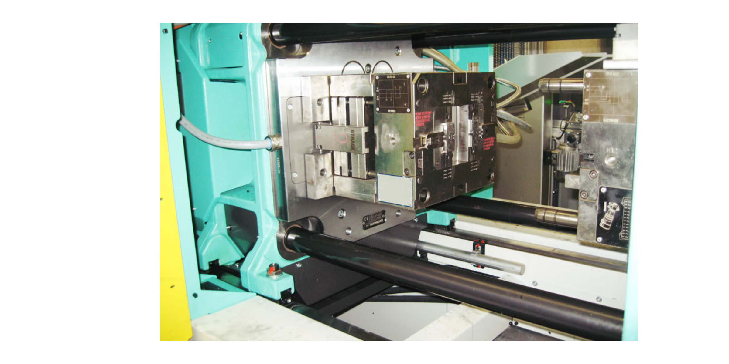 Close-up of industrial machinery with metal and black components, pipes, and electronic parts.