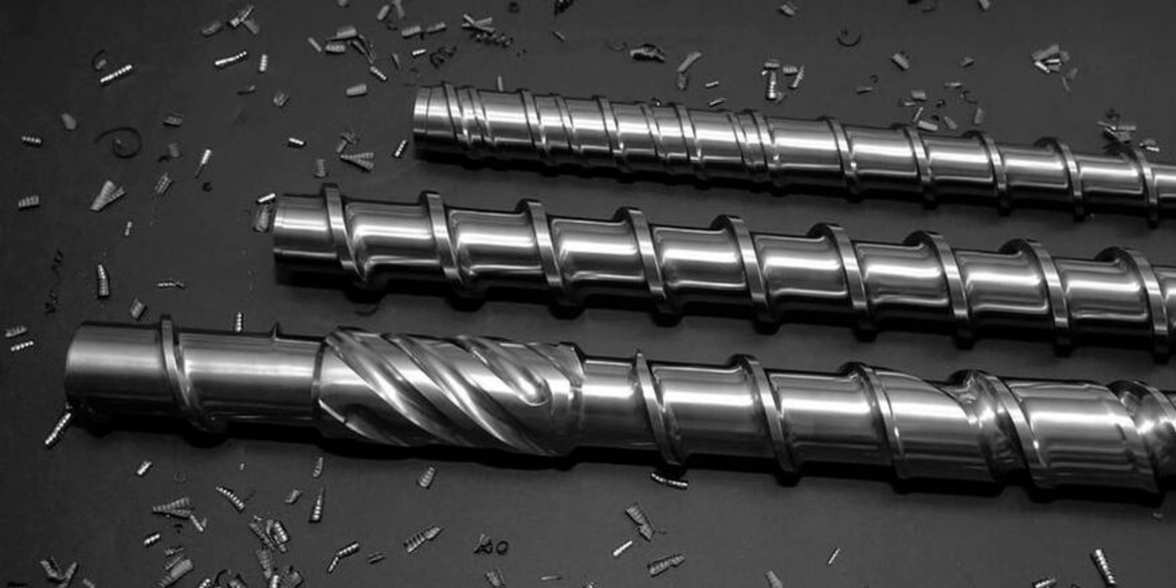 Large shiny metal cylindrical pipes with flanged ends resting on blue stands in an industrial factory setting.