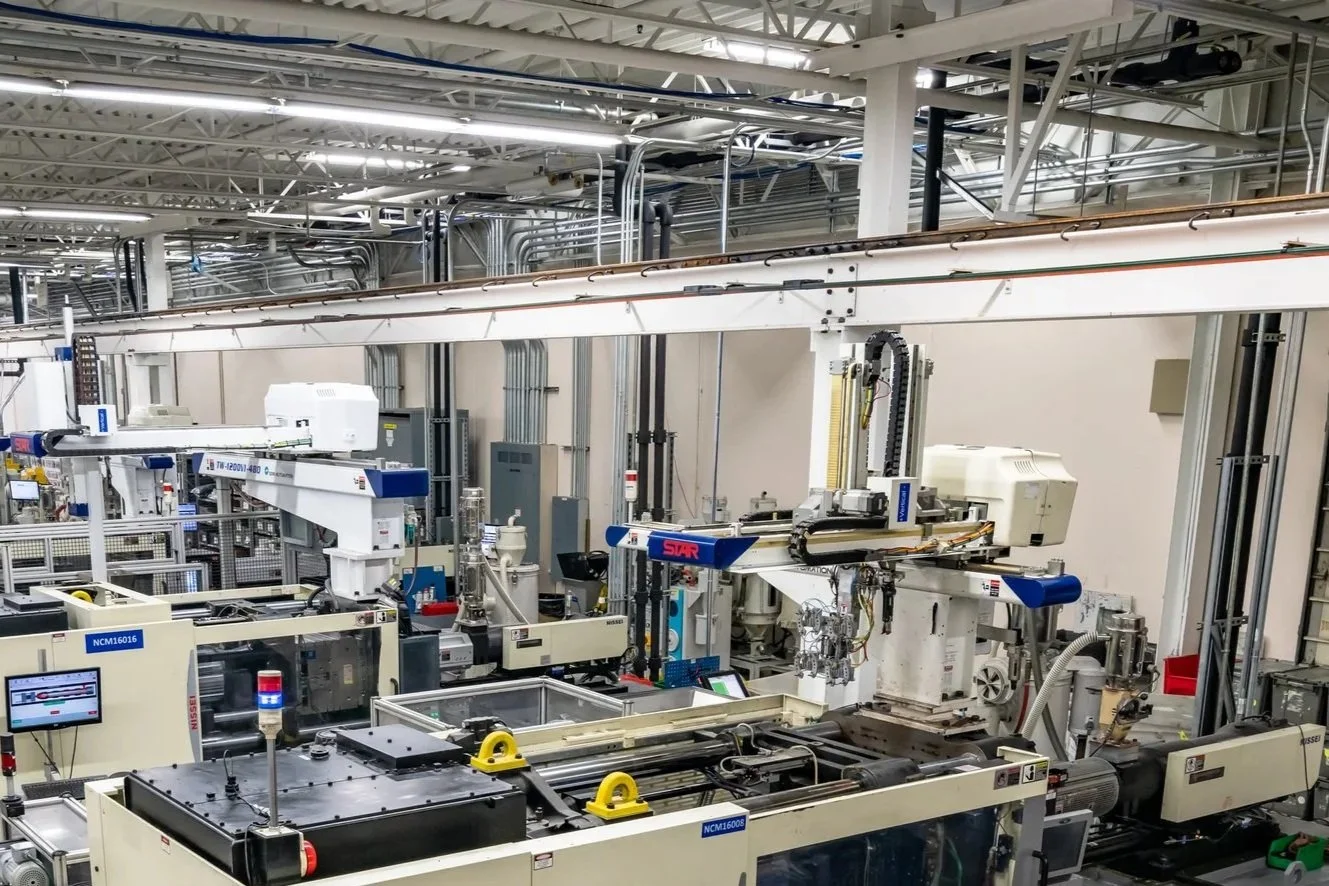 Industrial manufacturing facility with multiple large CNC machines arranged in rows within a spacious, well-lit factory