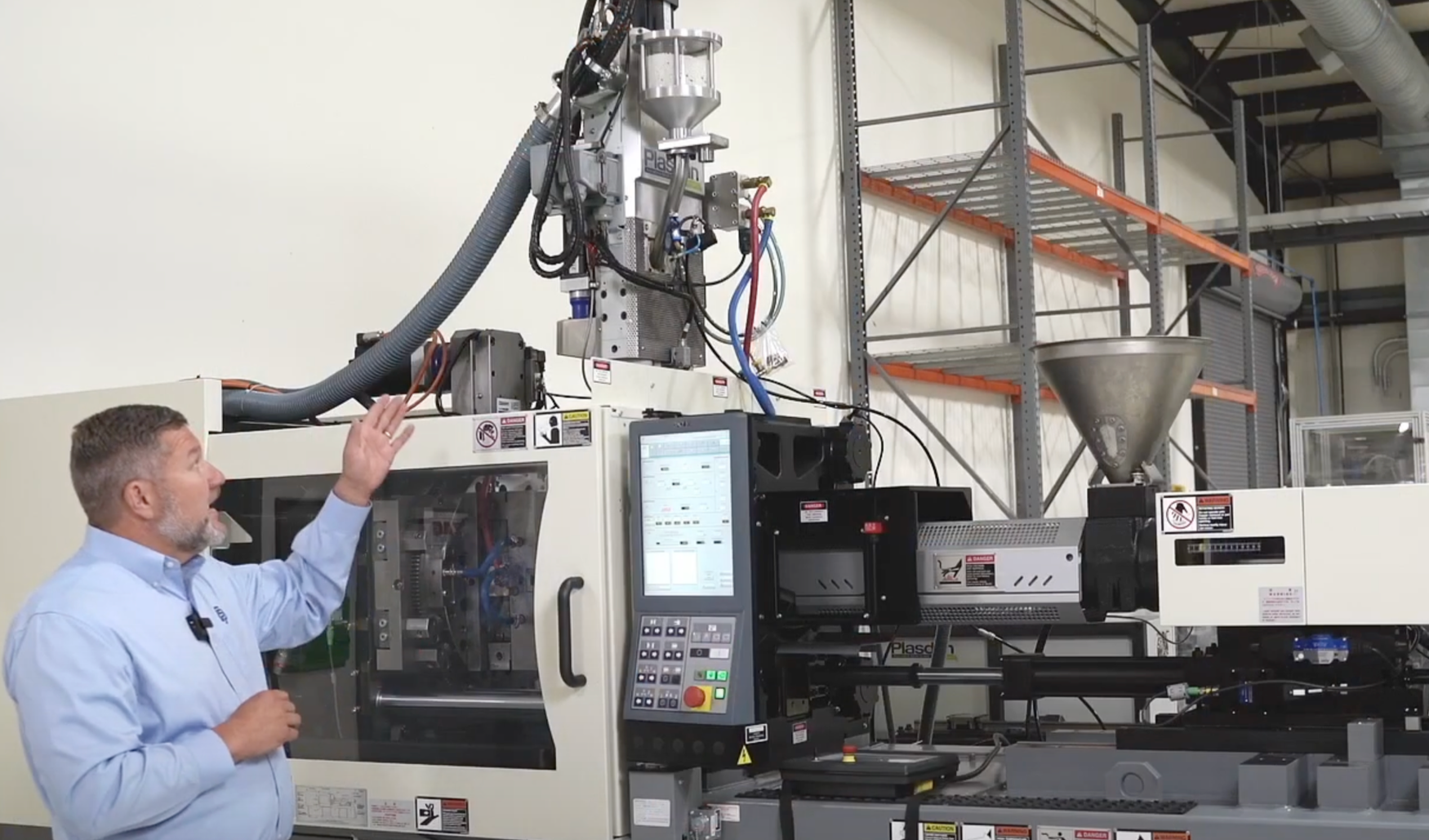 Man operating an industrial plastic injection molding machine in a manufacturing facility.
