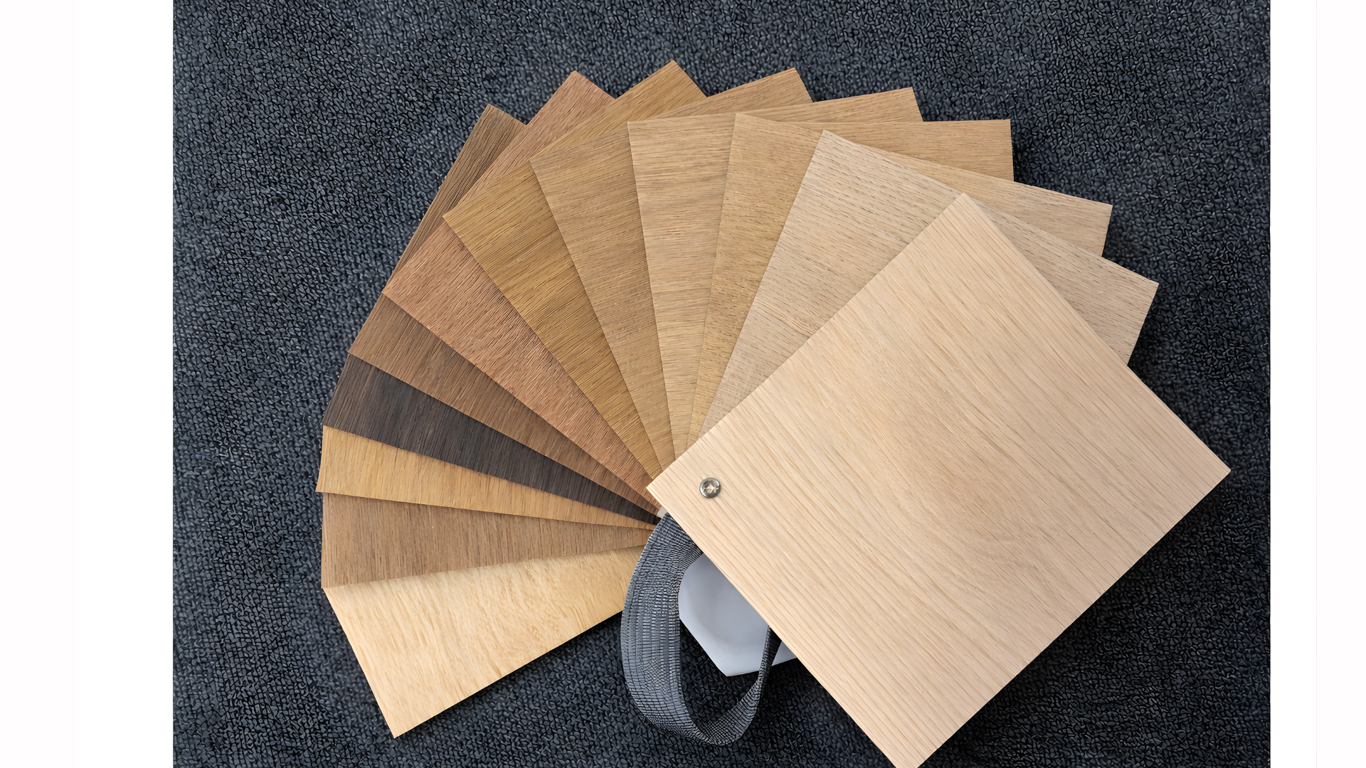Fanned display of wooden laminate sample swatches in various light and dark shades on a black textured surface.