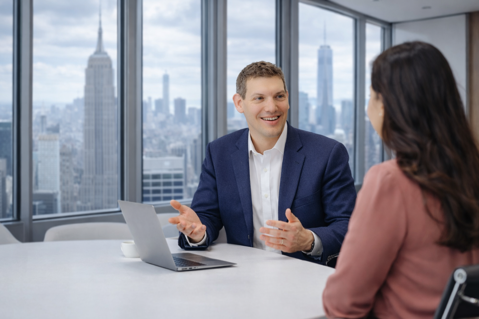 Josh Joffe meeting with a client in a modern office overlooking the New York City skyline.
