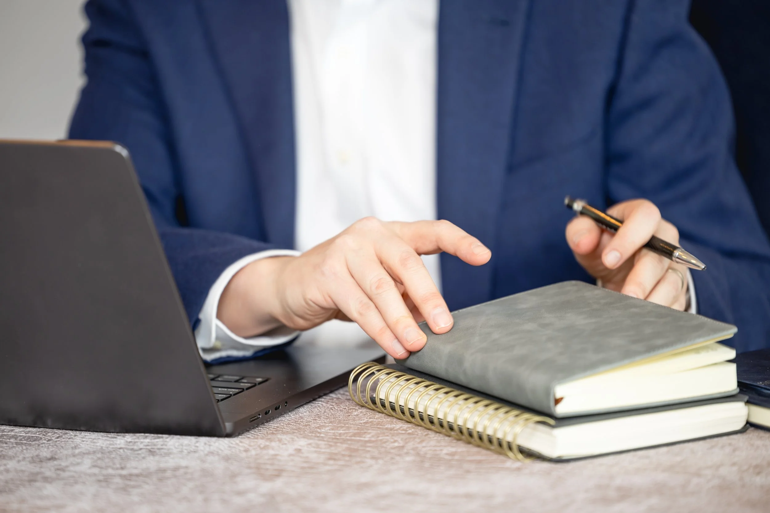 Financial advisor working at a desk with laptop and planner, reviewing notes and preparing financial strategy.