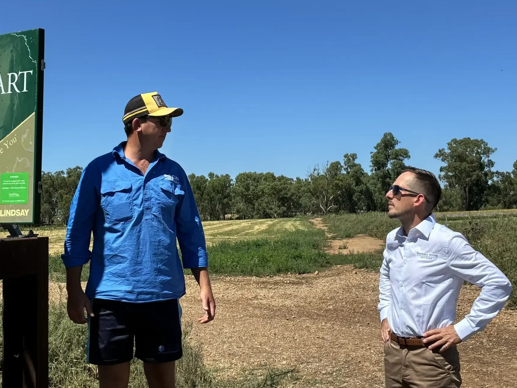 Rob standing outdoors, having a discussion with a client in front of a paddock.