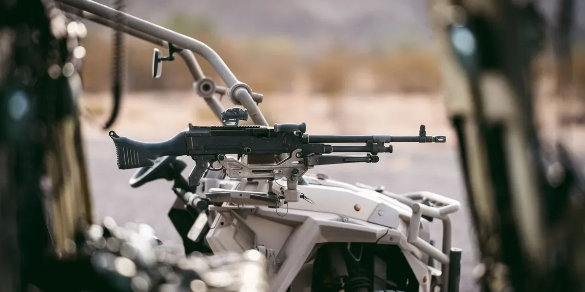 A sniper rifle mounted on a military motorcycle with a blurry background.