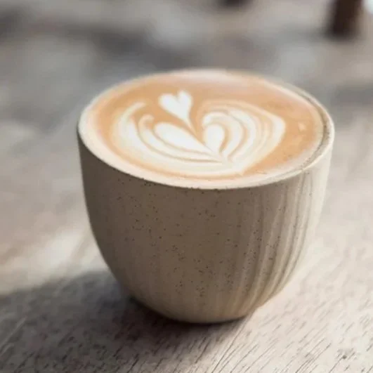 A cup of coffee with latte art in the shape of a heart and swirls.