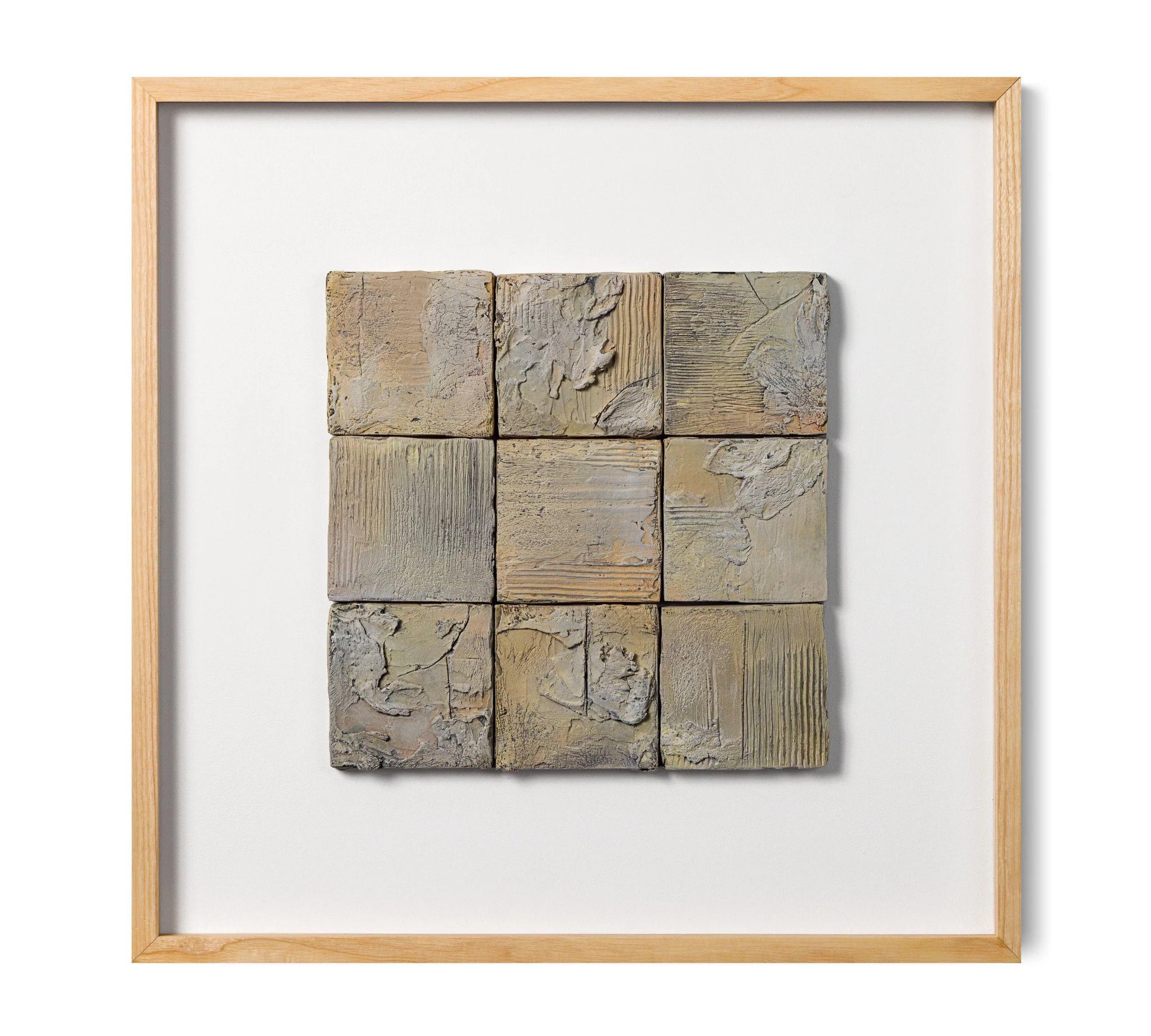 Nine square beige and gray textured stone tiles arranged in a 3x3 grid, framed with a light wooden border.