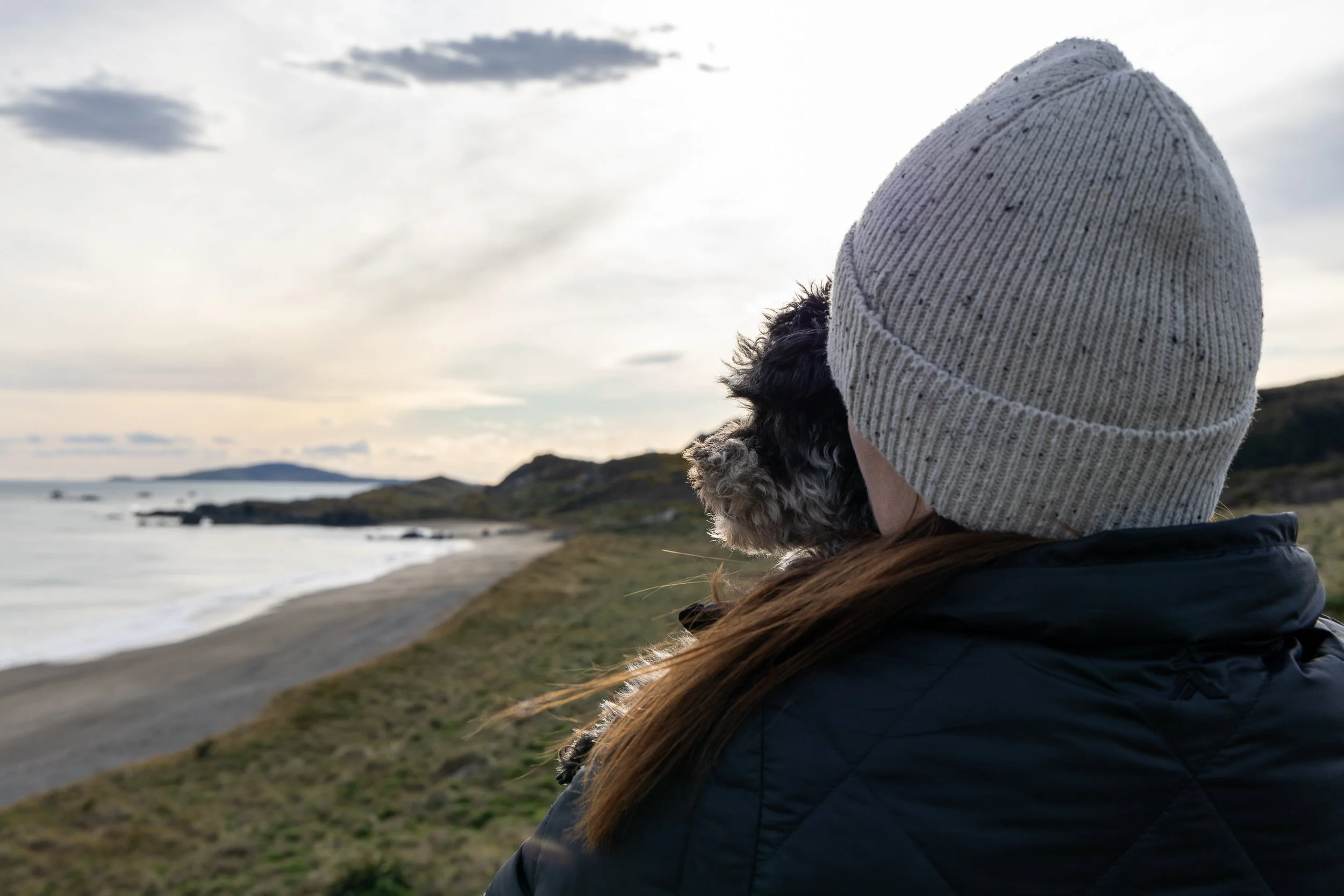 An image of a woman and dog looking out to sea.