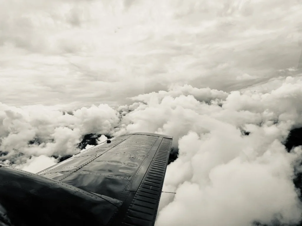 View from an airplane window showing part of the wing and a cloudy sky.